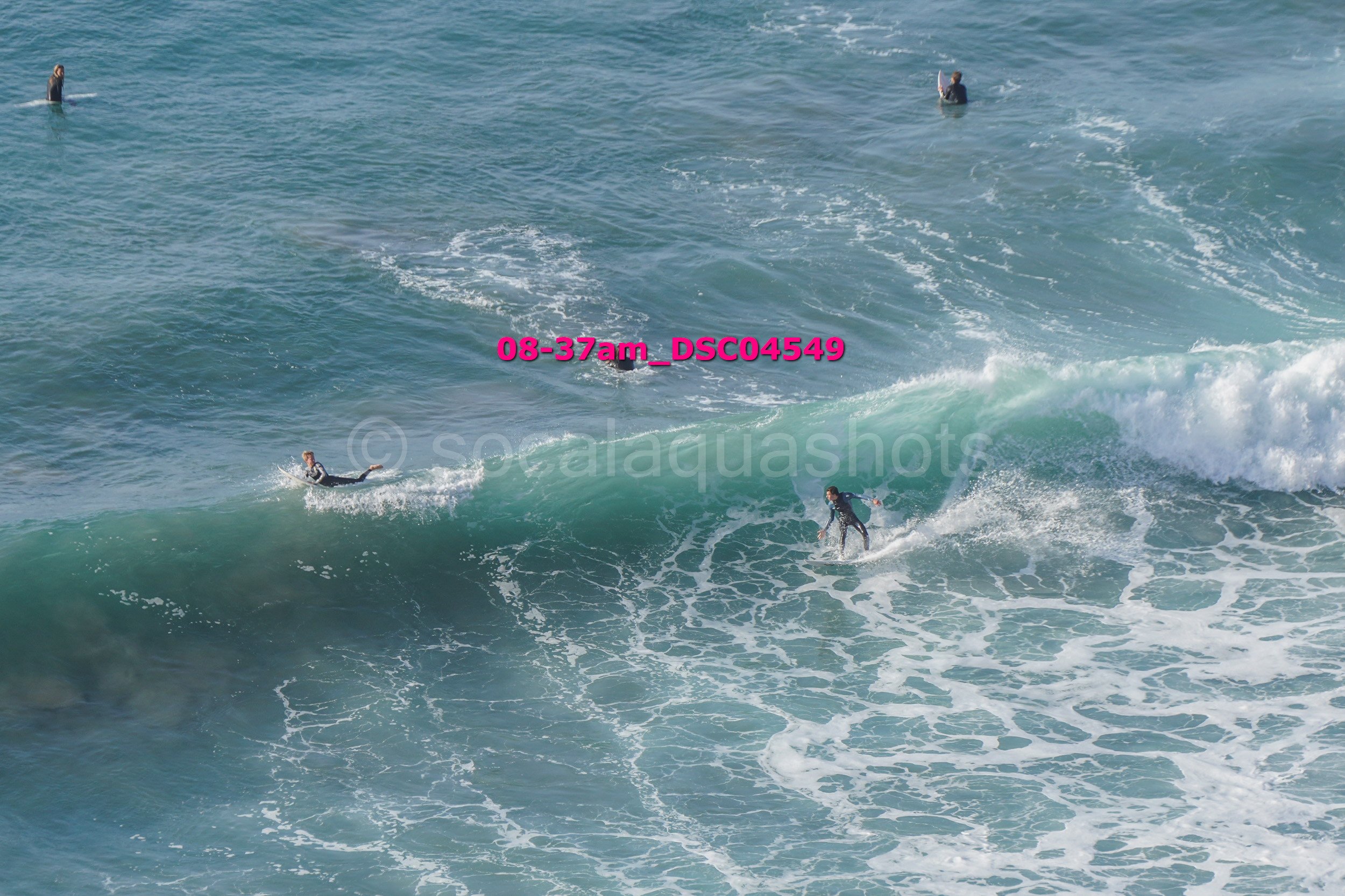 Several surfers riding and waiting on ocean waves in the sea.
