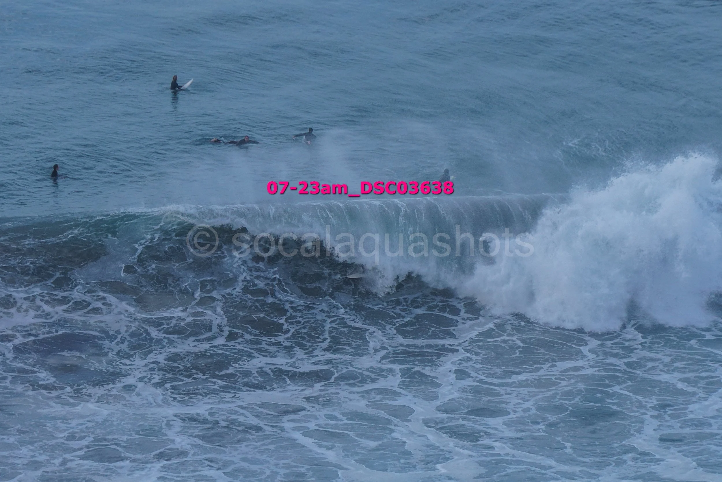Multiple surfers in the ocean near a large breaking wave
