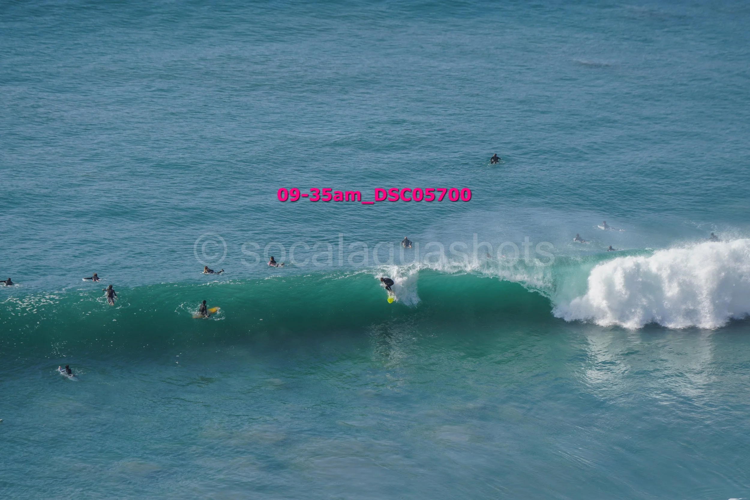 Surfer riding a wave with multiple surfers in the water around him.