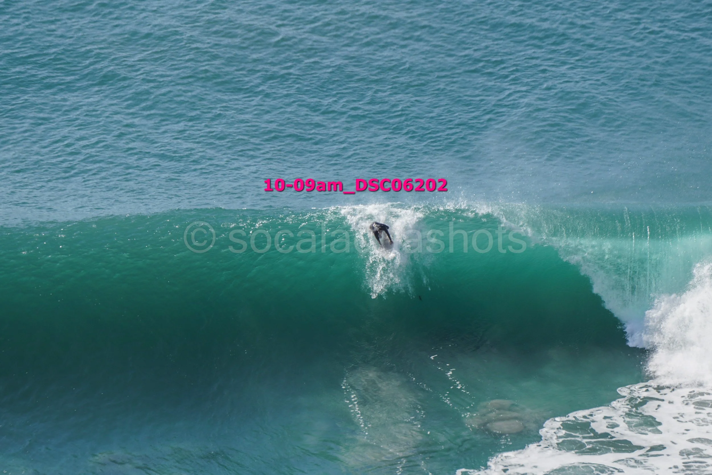 A person surfing on a large ocean wave with the surfboard in the water.