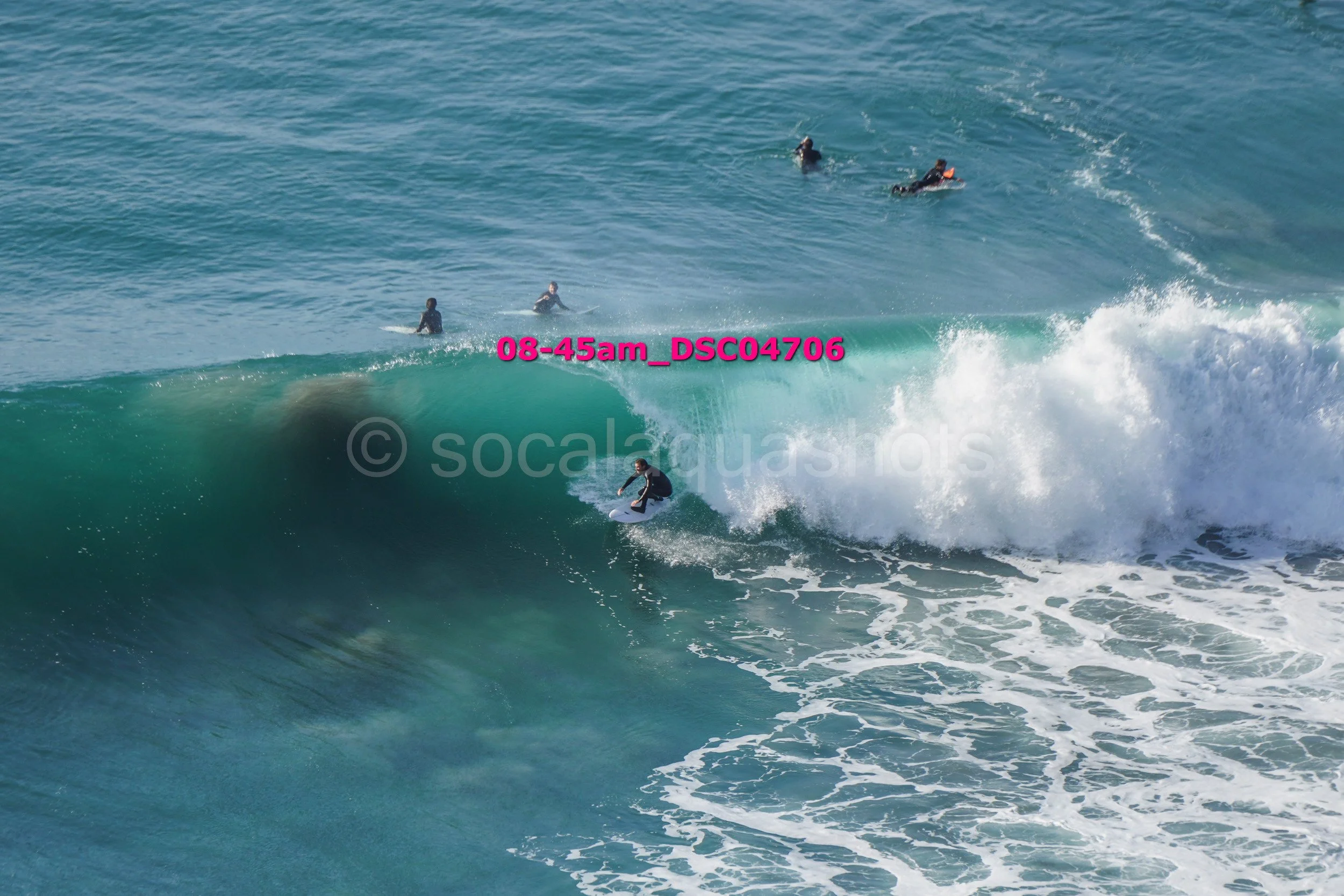 Surfer riding a wave with several surfers in the water behind him.