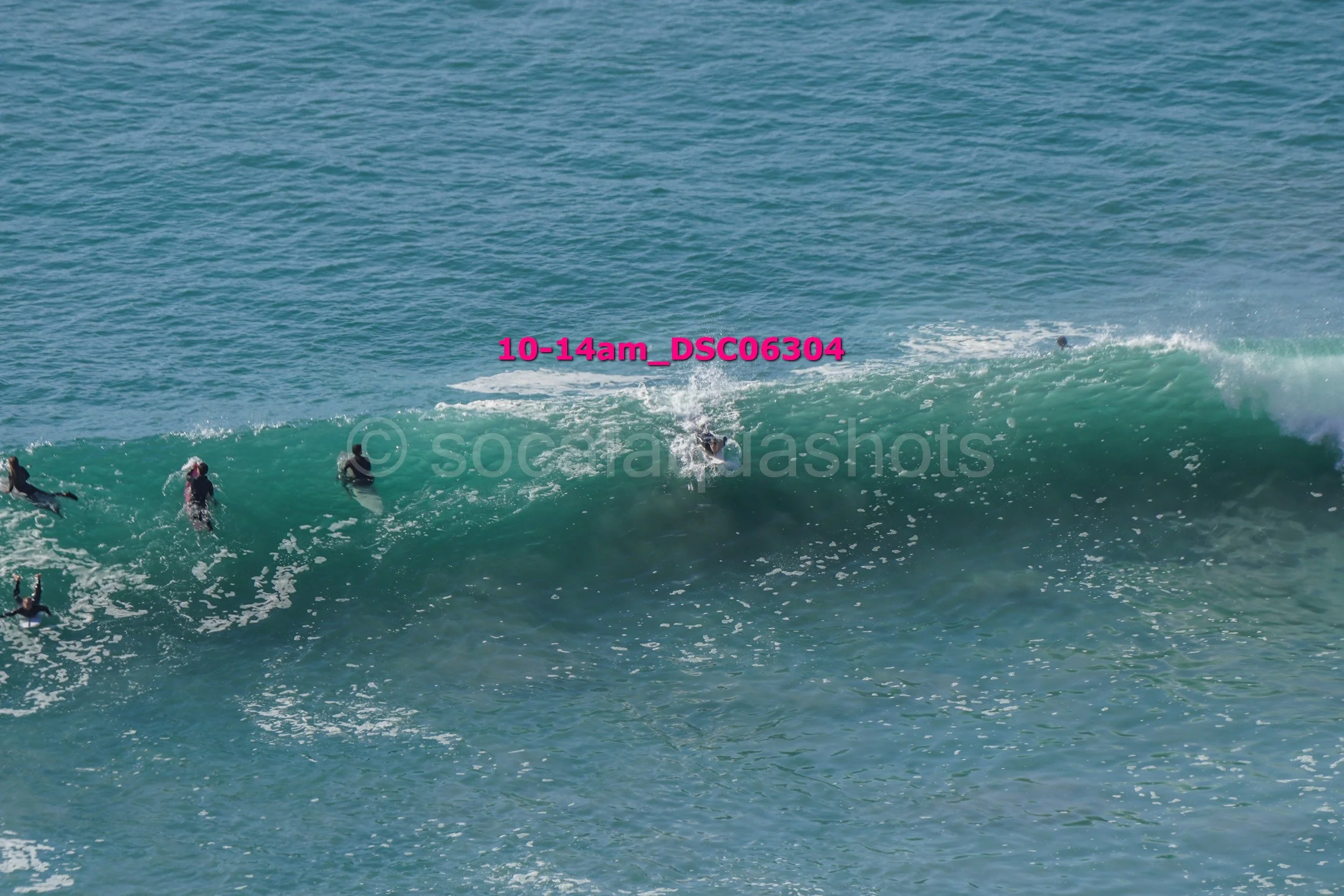 A group of people surfing on a large ocean wave.