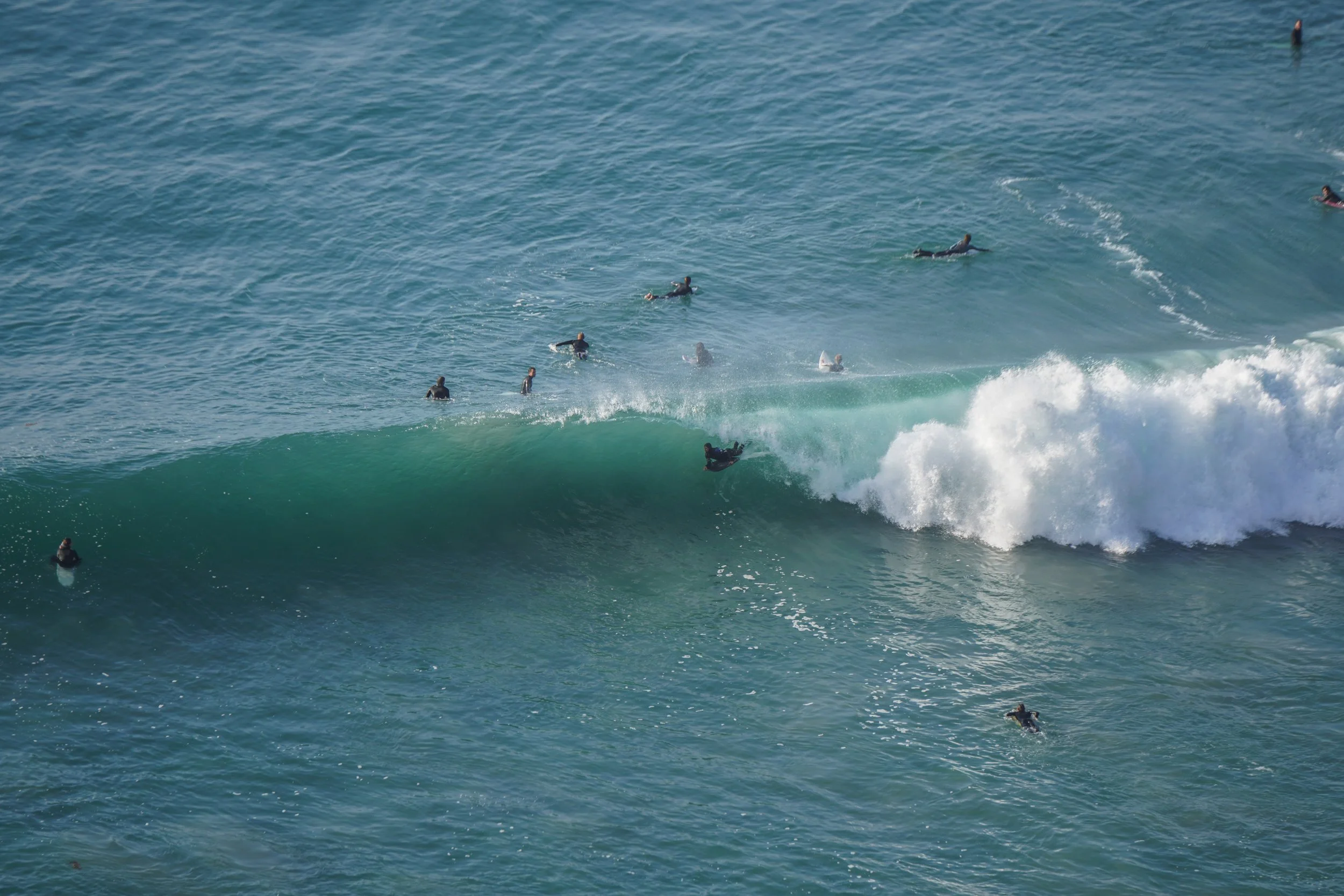 Surfers riding a wave while others wait in the water
