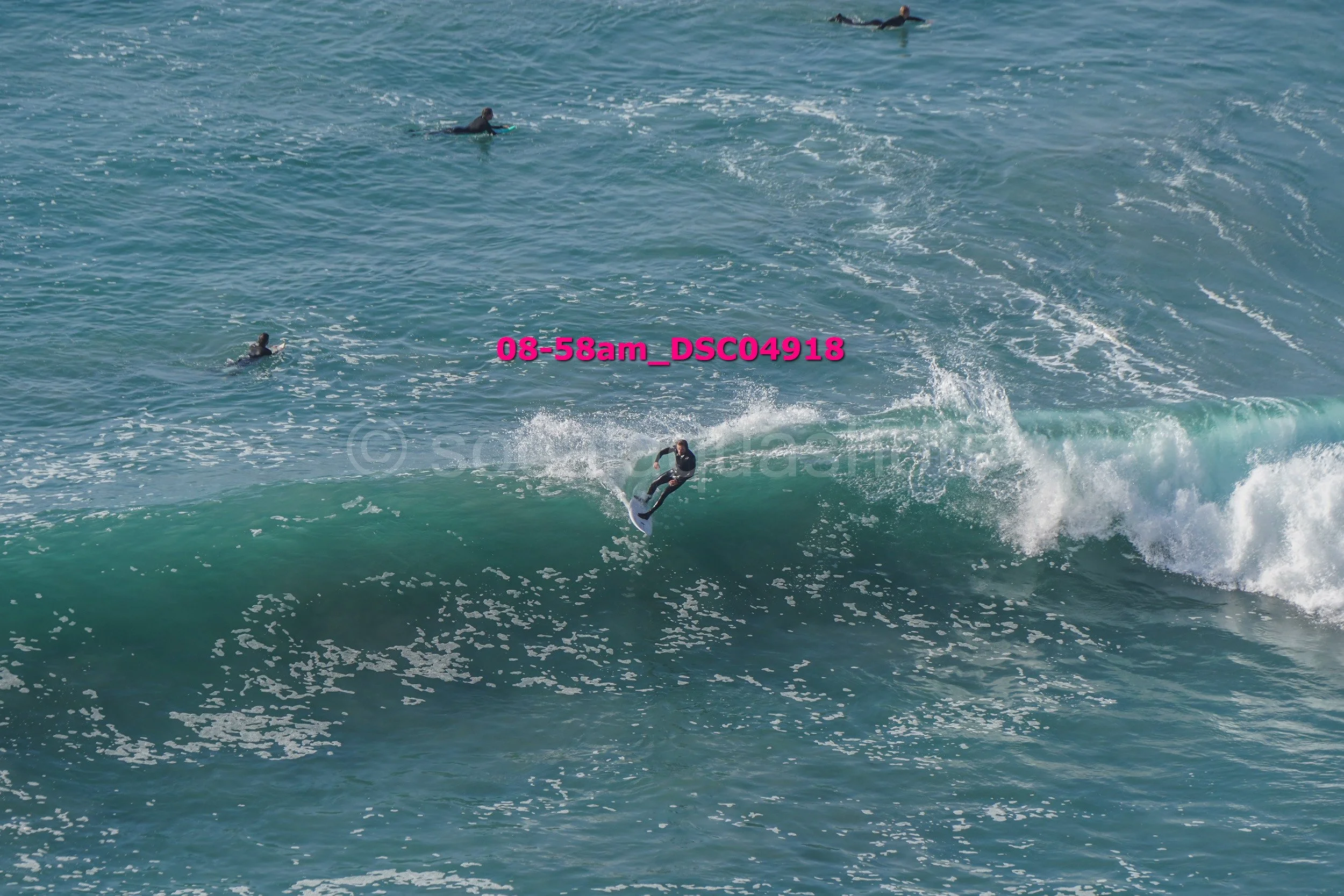 Surfer riding a wave with several surfers in the water in the background.