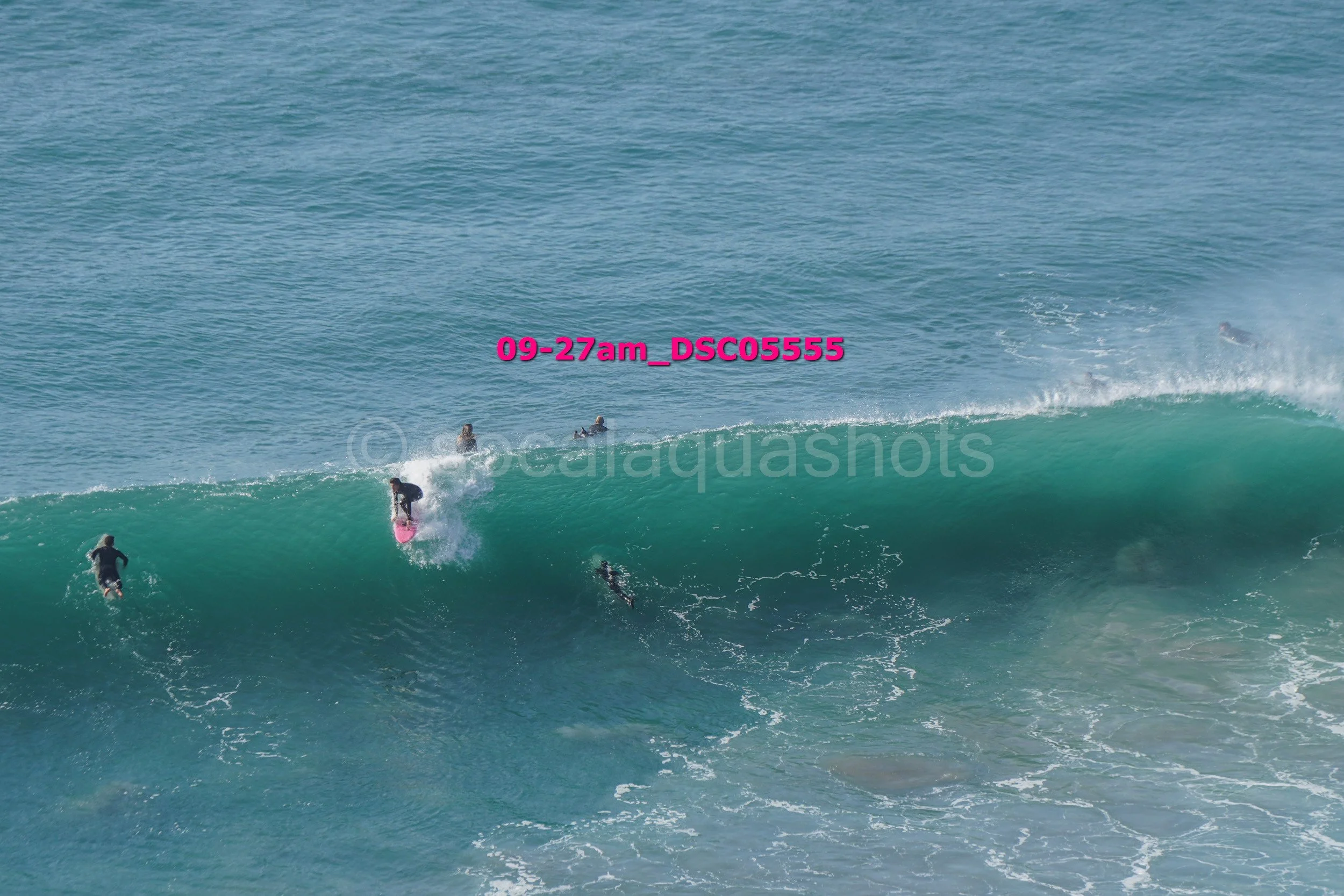 People surfing on a large ocean wave during daytime.