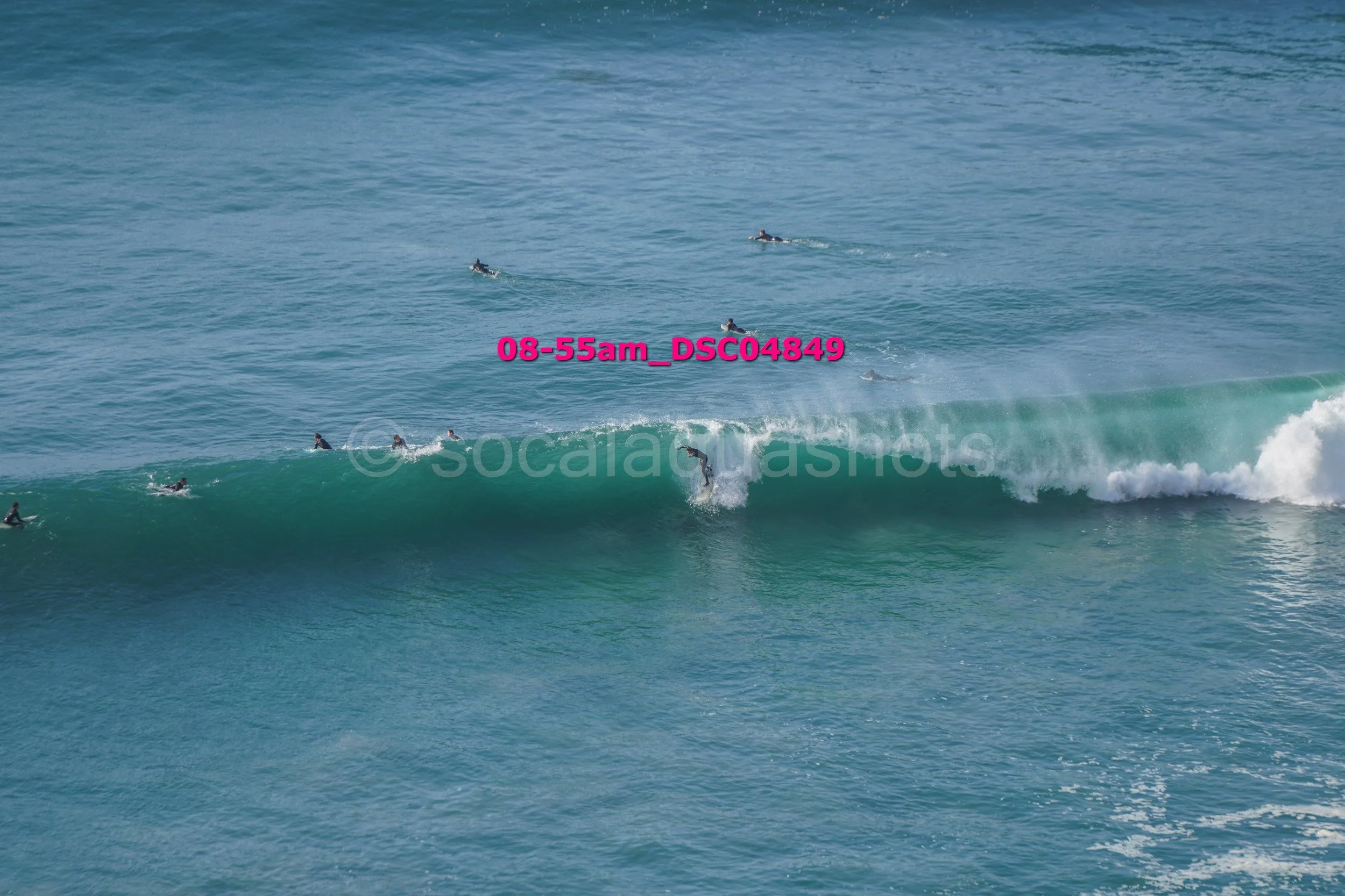 Surfer riding a wave with several surfers in the water nearby.