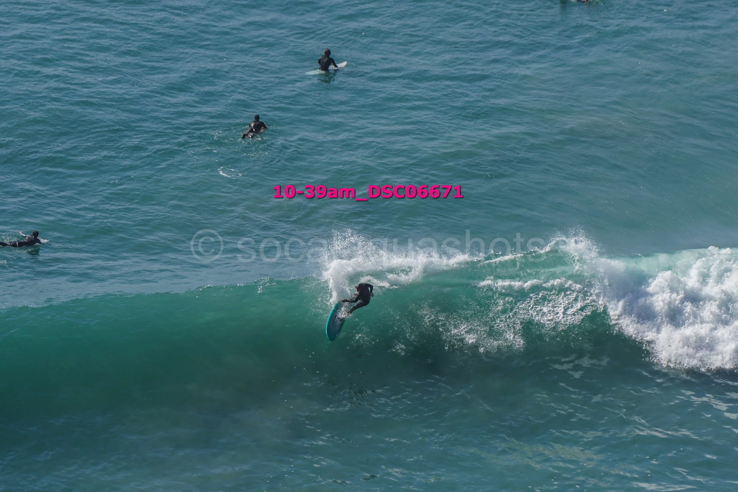 Surfer riding a wave while four other surfers are in the water watching.