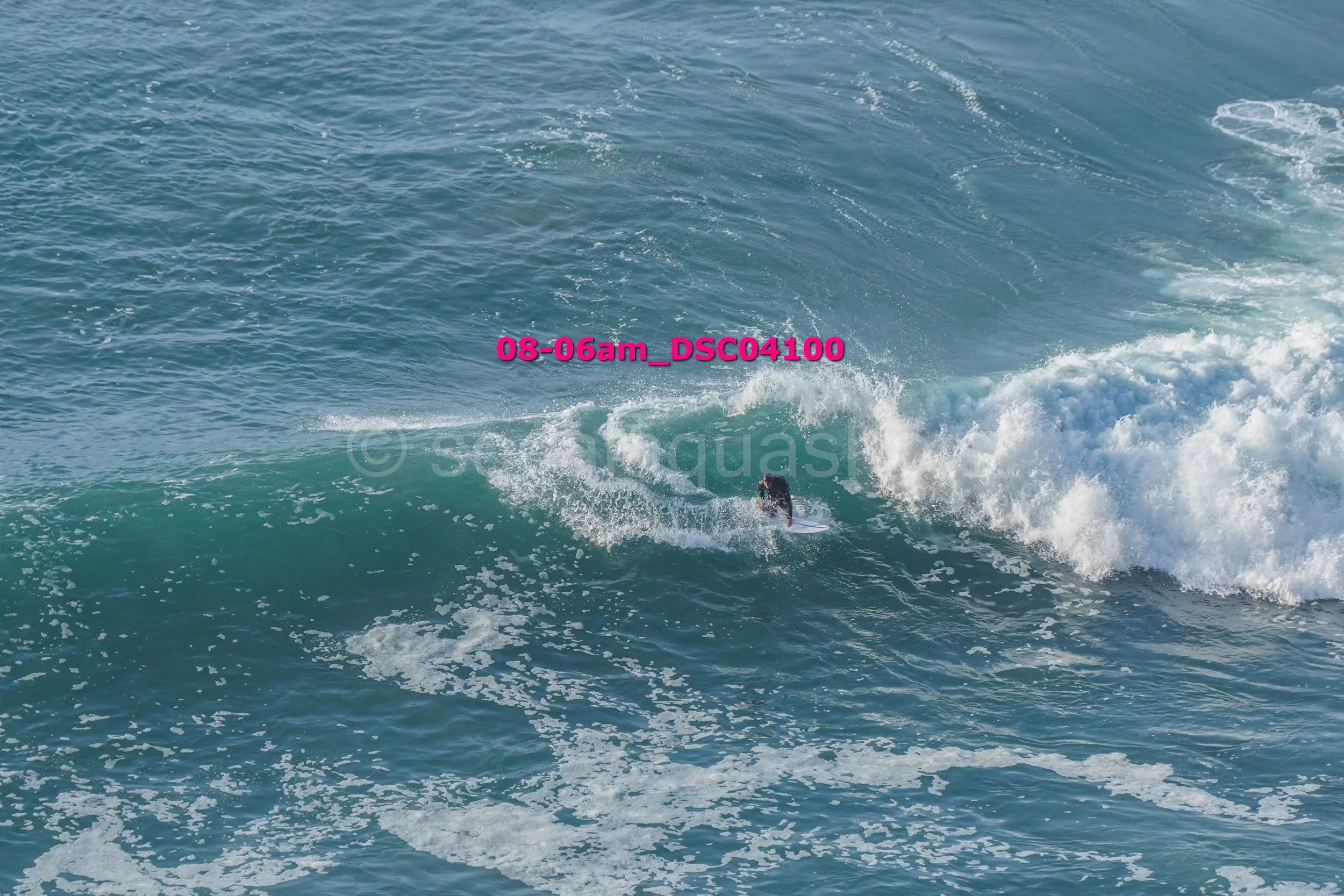 A person surfing on a large wave in the ocean.