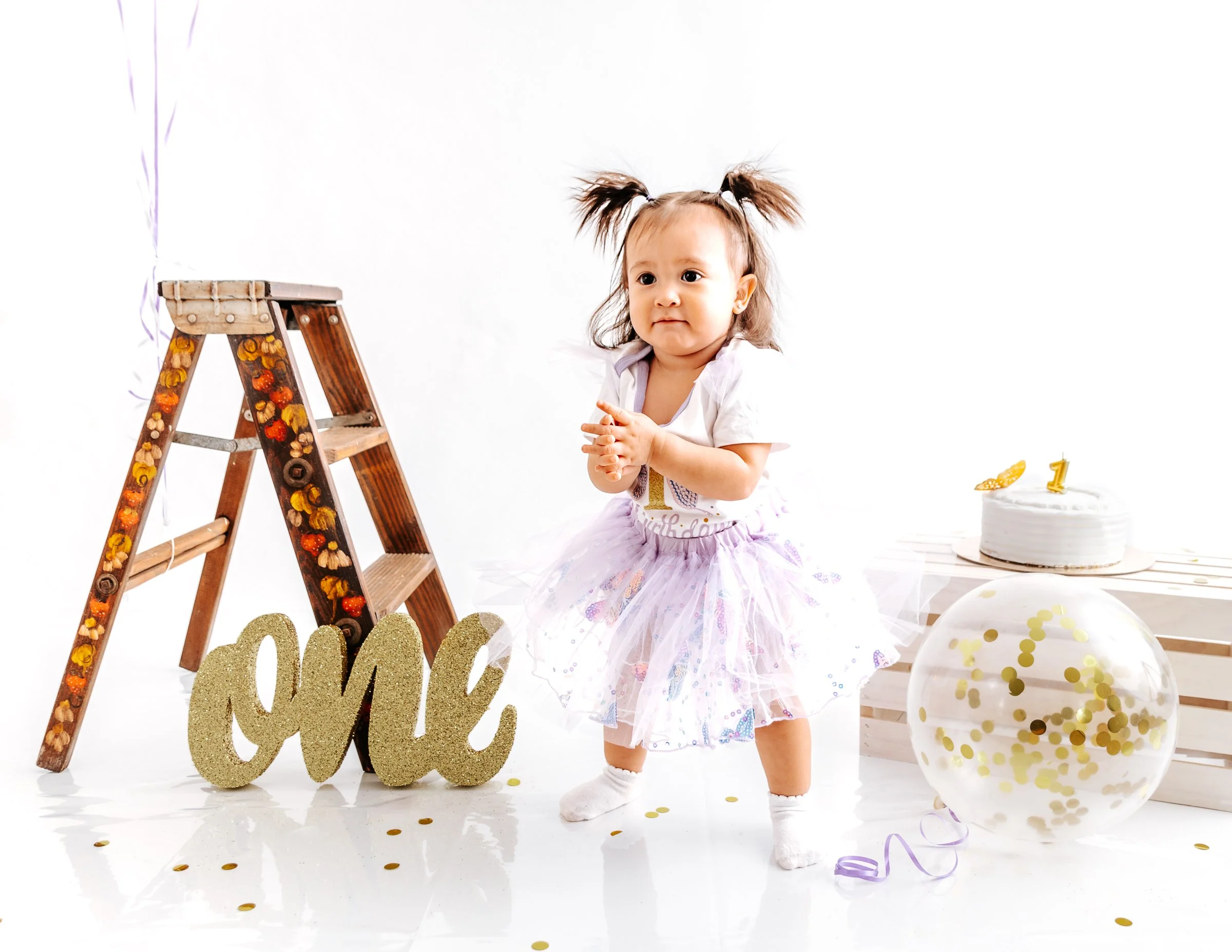 smash cake, little girl turning one on a minimalist white drop with cake and balloons