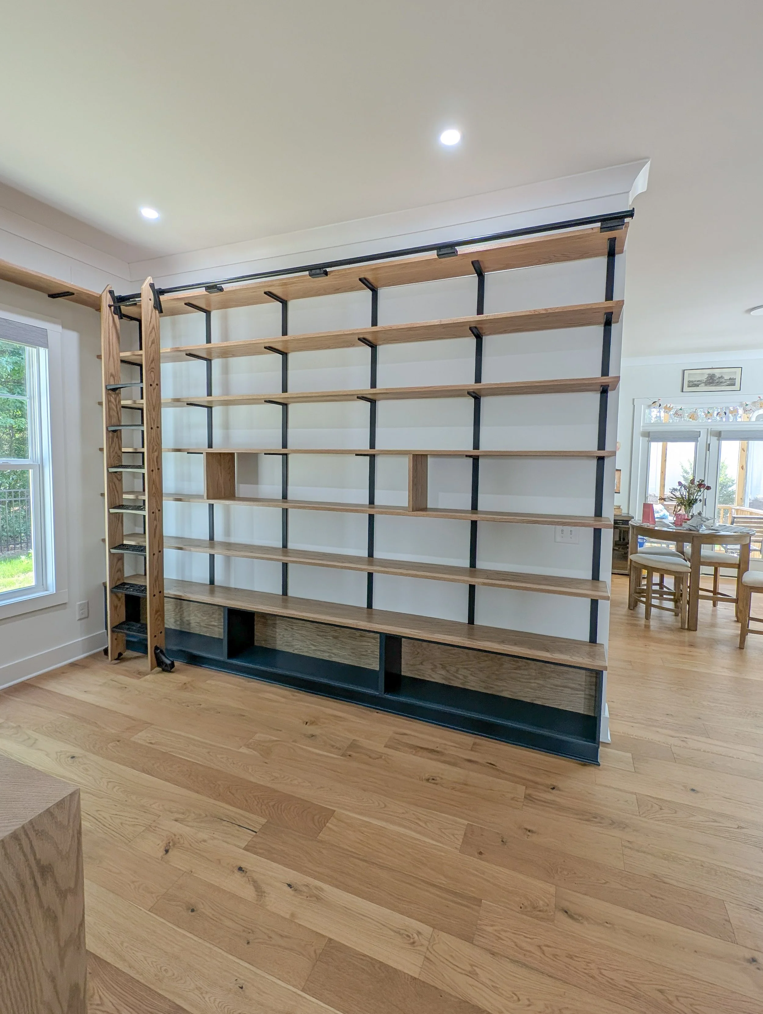 Library with dry bar. White oak shelving, countertops, cabinets and rolling ladder