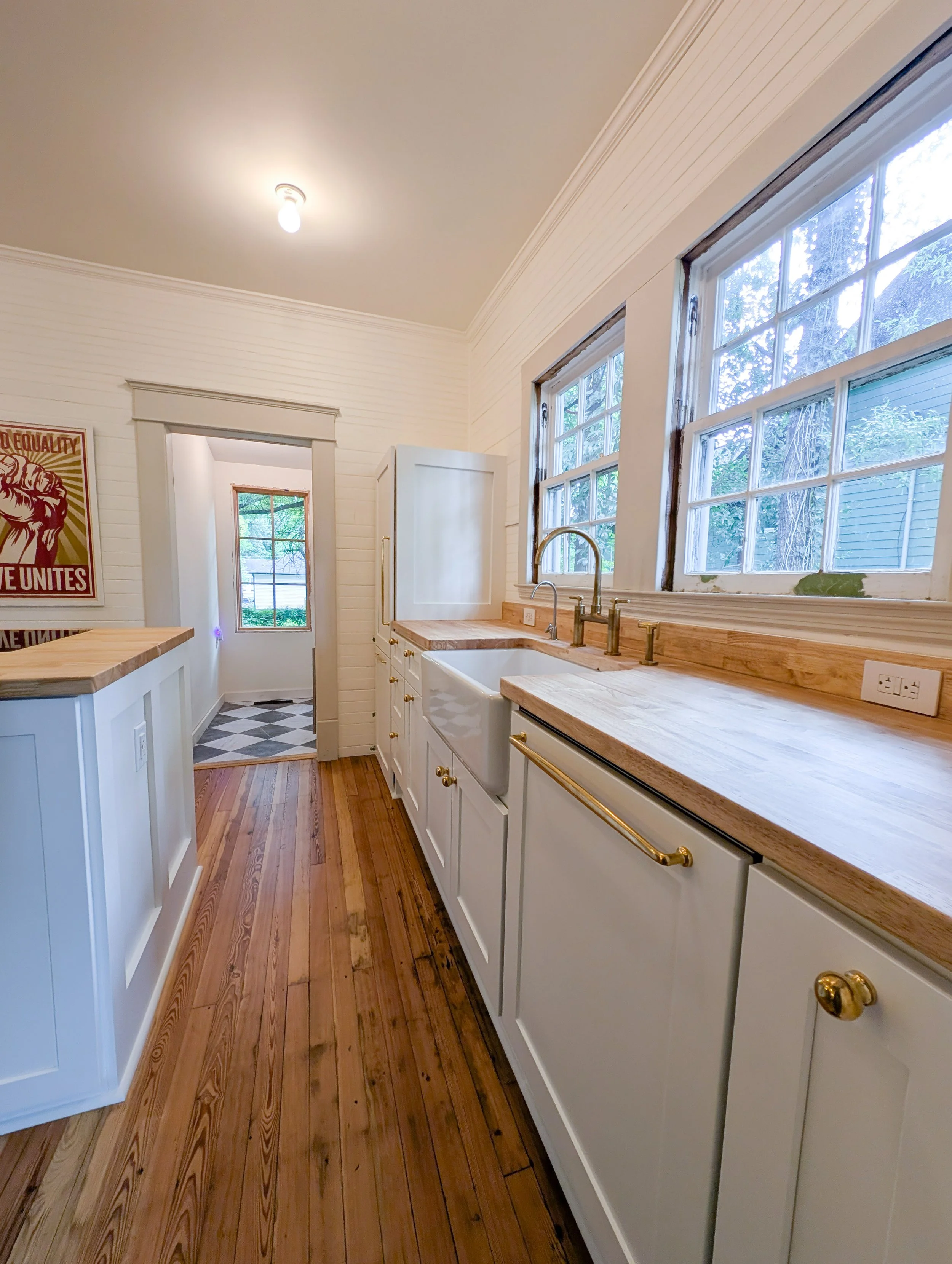 long angle view of sink and white shaker cabinets with butcher block counters