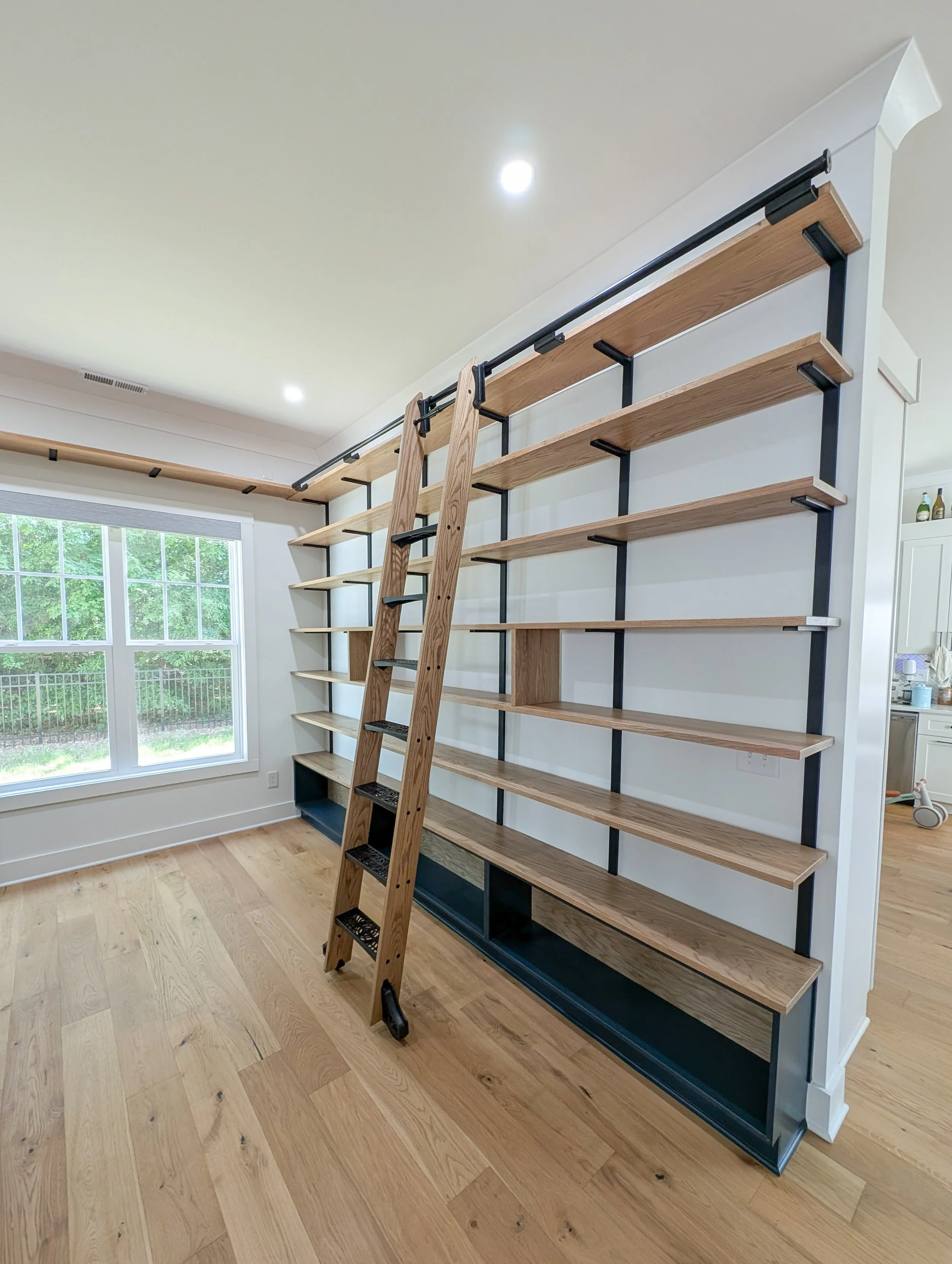 Library with dry bar. White oak shelving, countertops, cabinets and rolling ladder