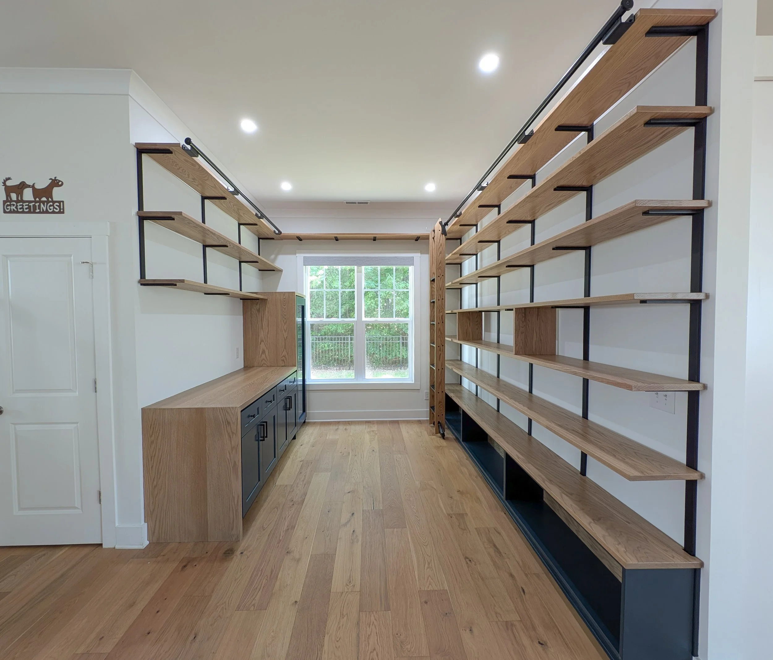 Library with dry bar. White oak shelving, countertops, cabinets and rolling ladder