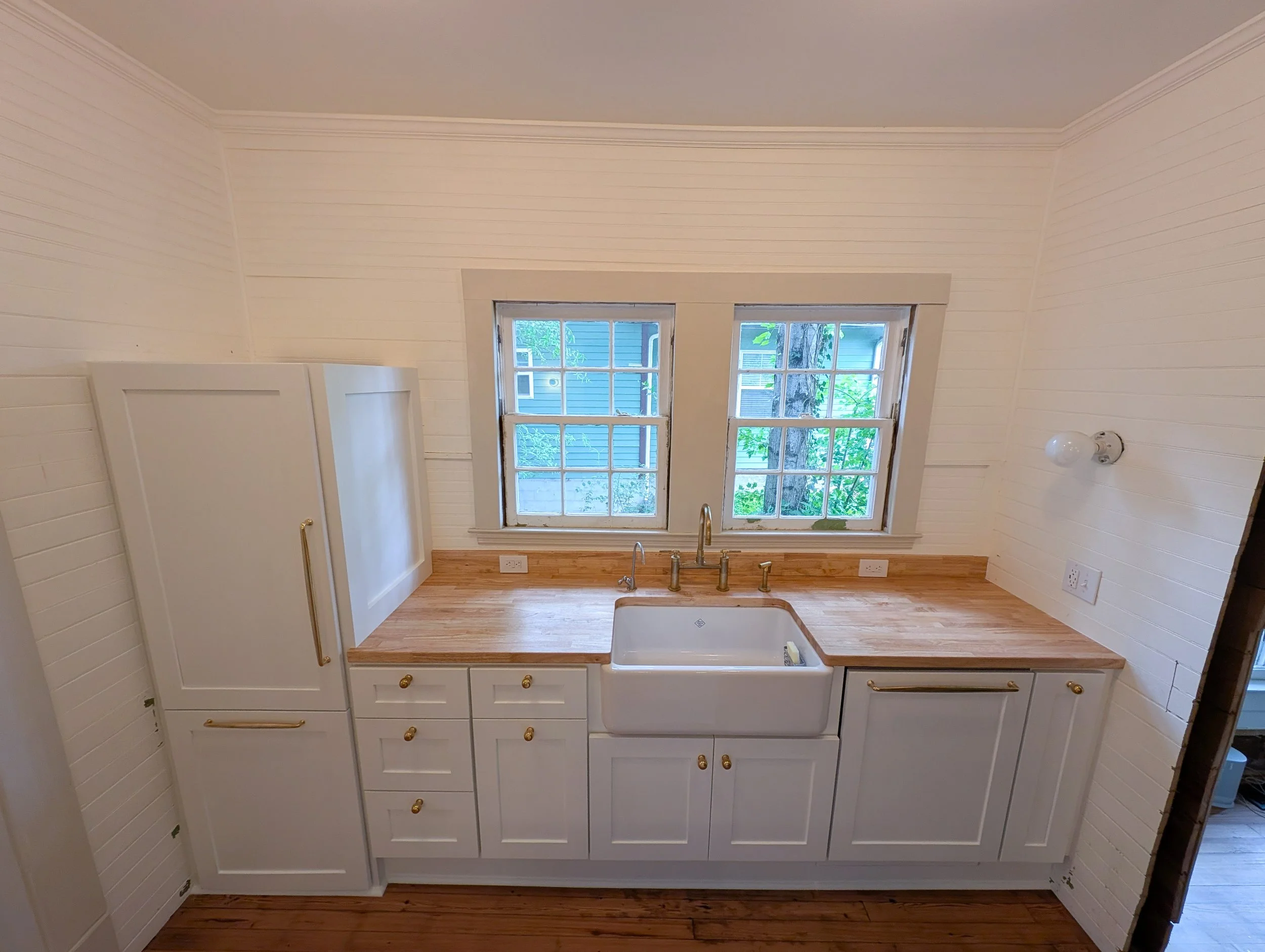 Top view of sink and refrigerator with white shaker cabinets and butcher block cabinets