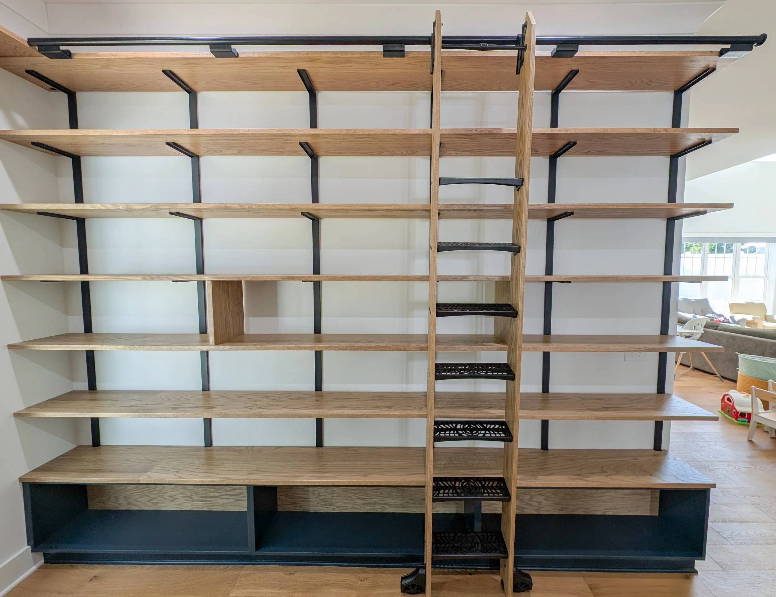 Library with dry bar. White oak shelving, countertops, cabinets and rolling ladder