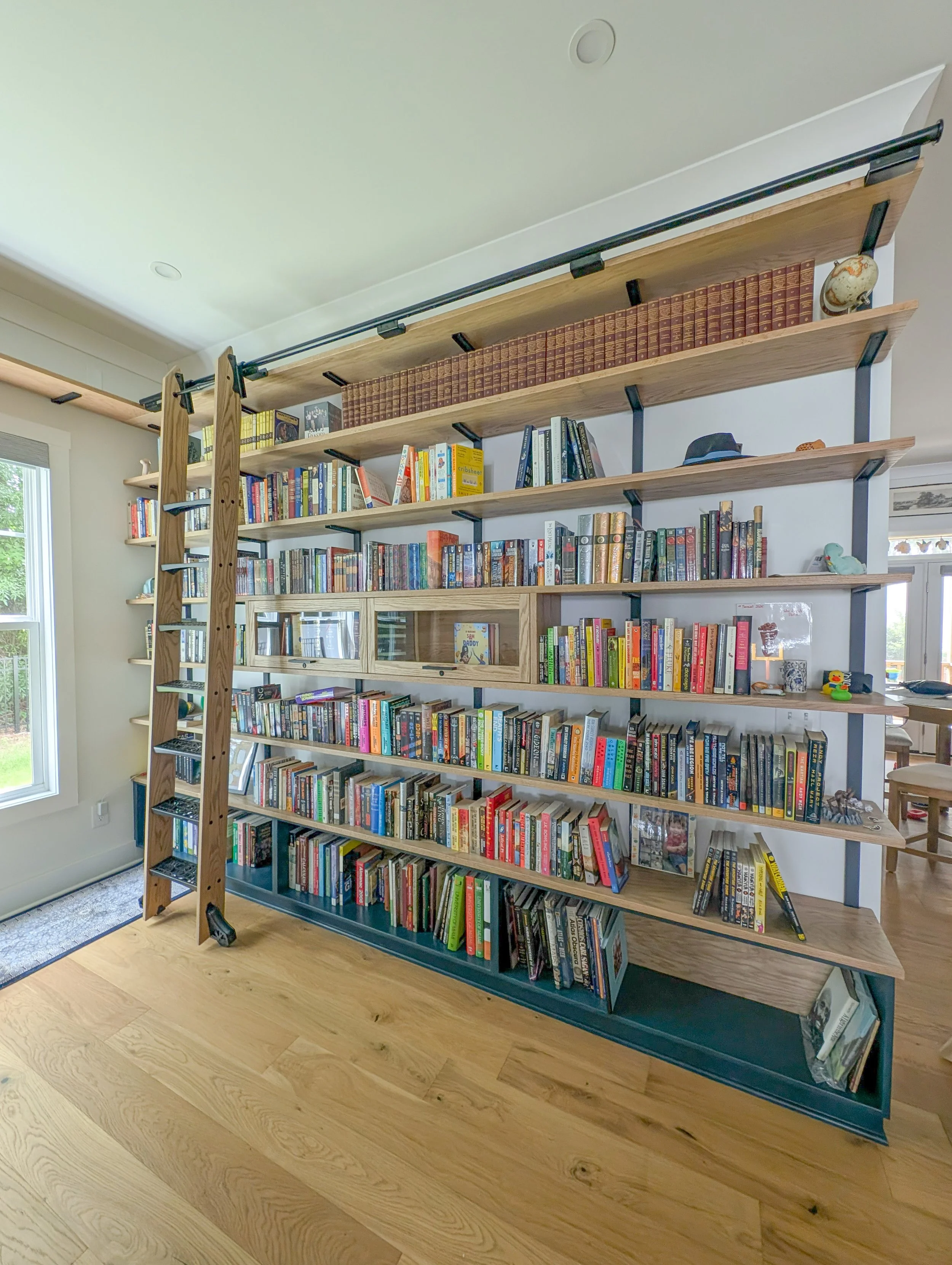 Library with dry bar. White oak shelving, countertops, cabinets and rolling ladder