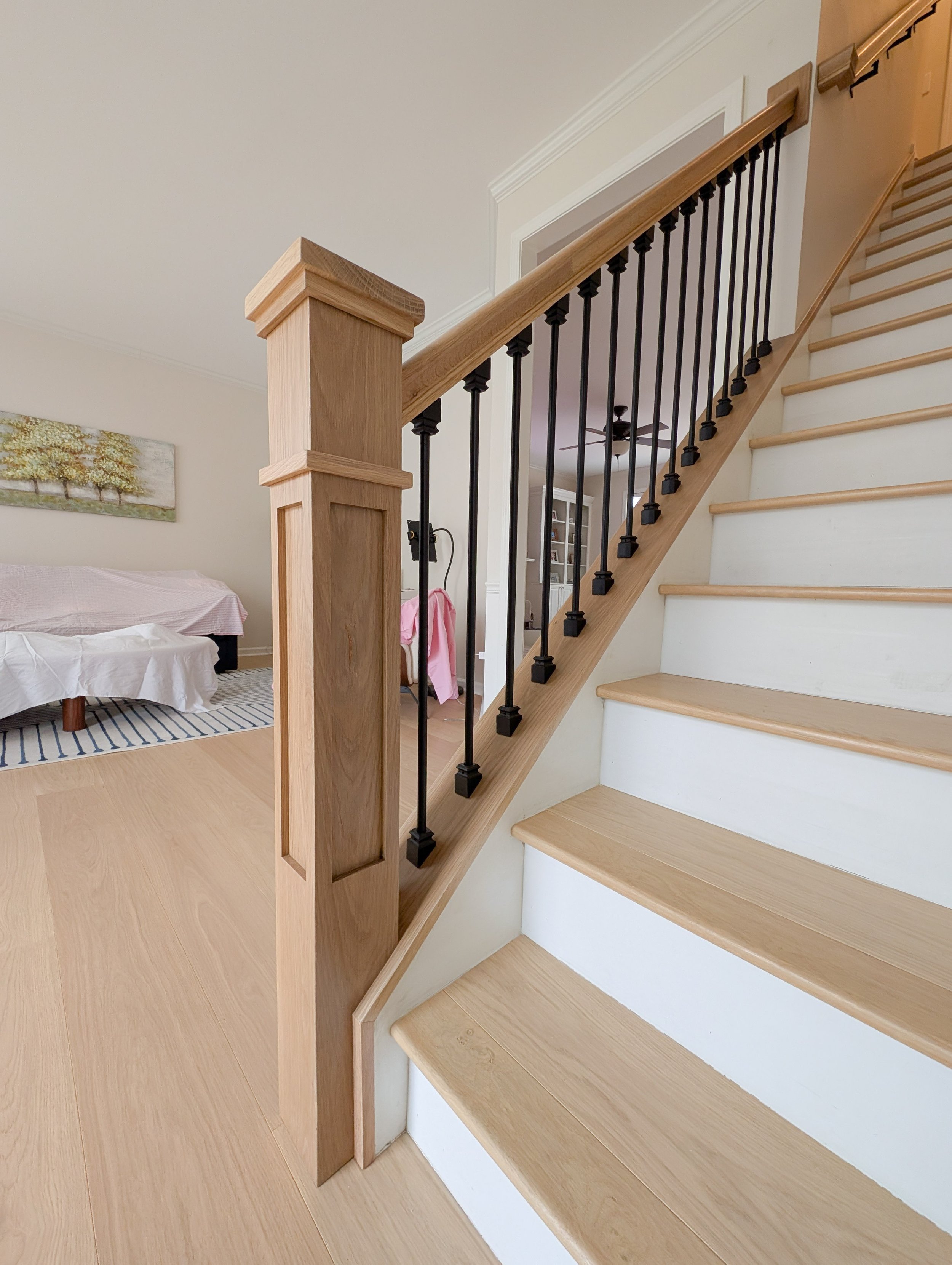 White oak newel post and banister with black metal balusters