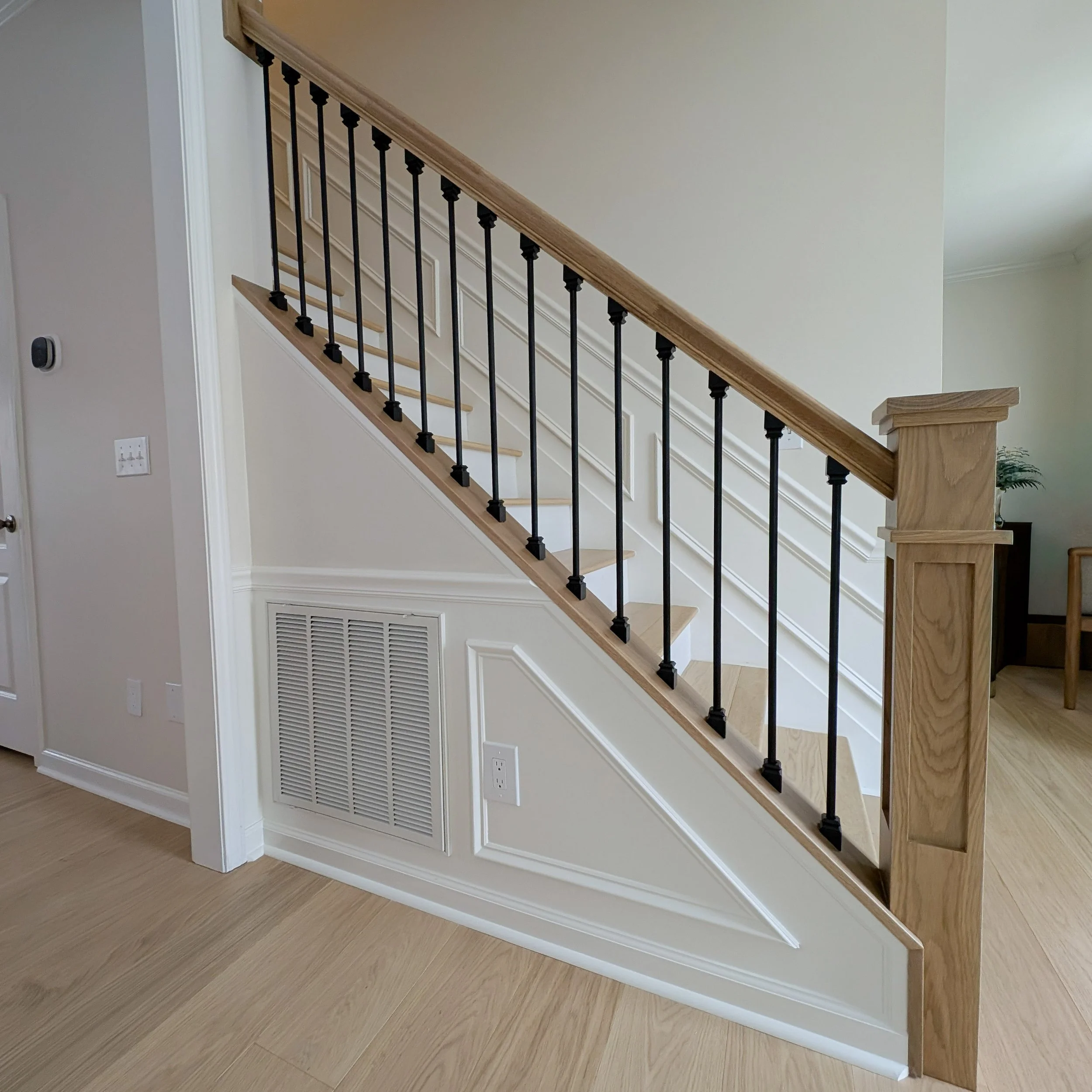 White oak newel post and banister with black metal balusters