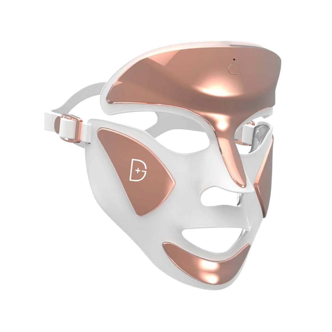 A white and rose gold Dr. Dennis Gross LED light therapy face mask with a futuristic, contoured design.
