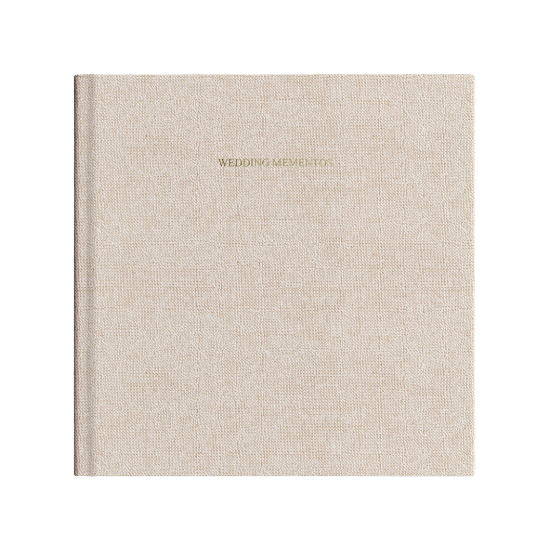 A square, champagne-colored linen hardcover photo album with a minimalist title embossed in gold on the front.