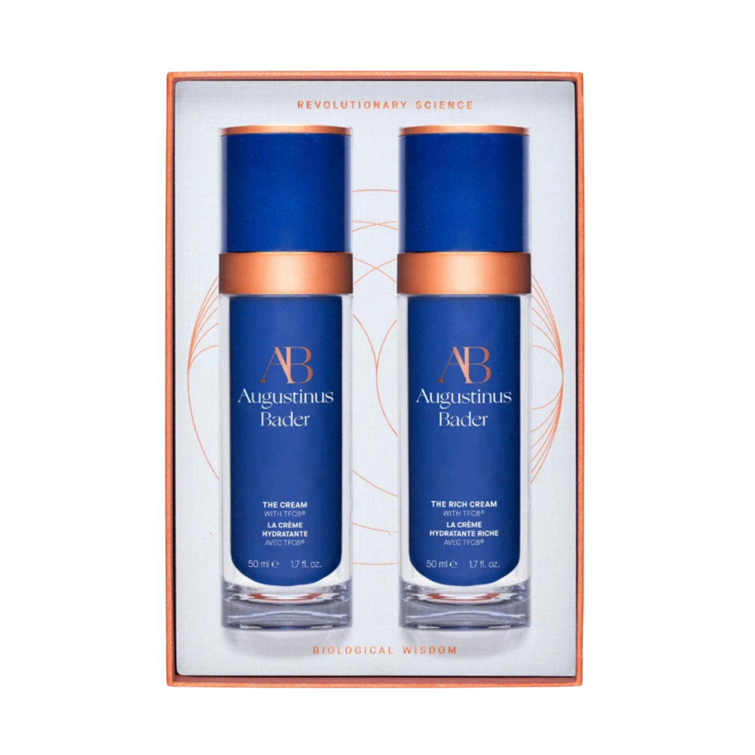 An Augustinus Bader gift set featuring two luxury blue and copper glass bottles of face cream in a decorative box.