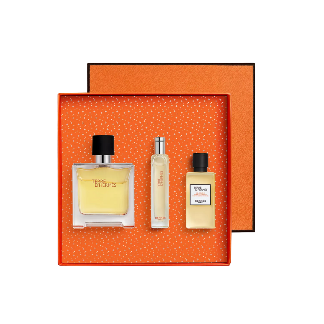 An Hermès gift set in a vibrant orange box featuring a full-sized glass cologne bottle, a travel spray, and a small aftershave.