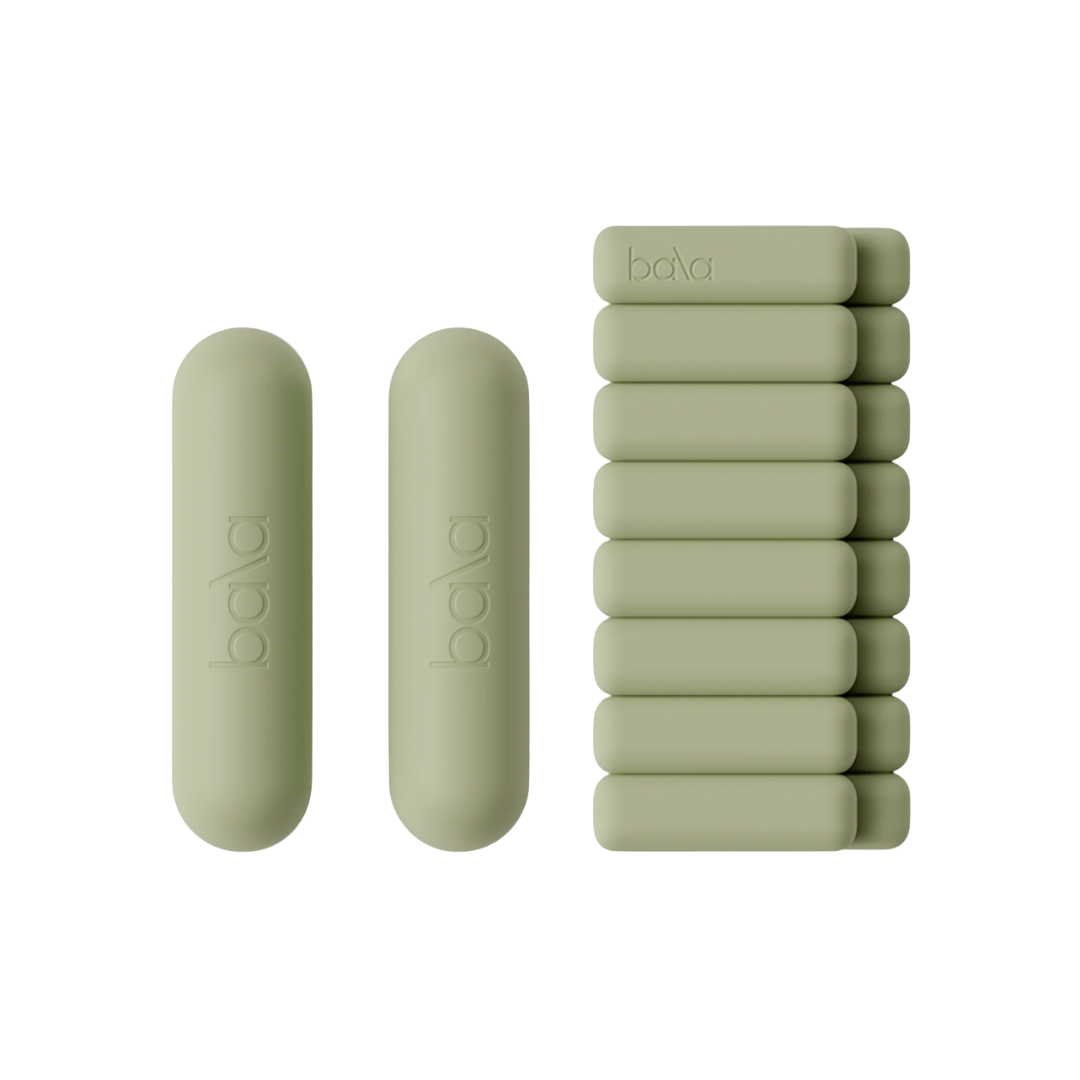 A set of sage green Bala fitness accessories, including two weighted bars and a stack of matching weighted bangles.
