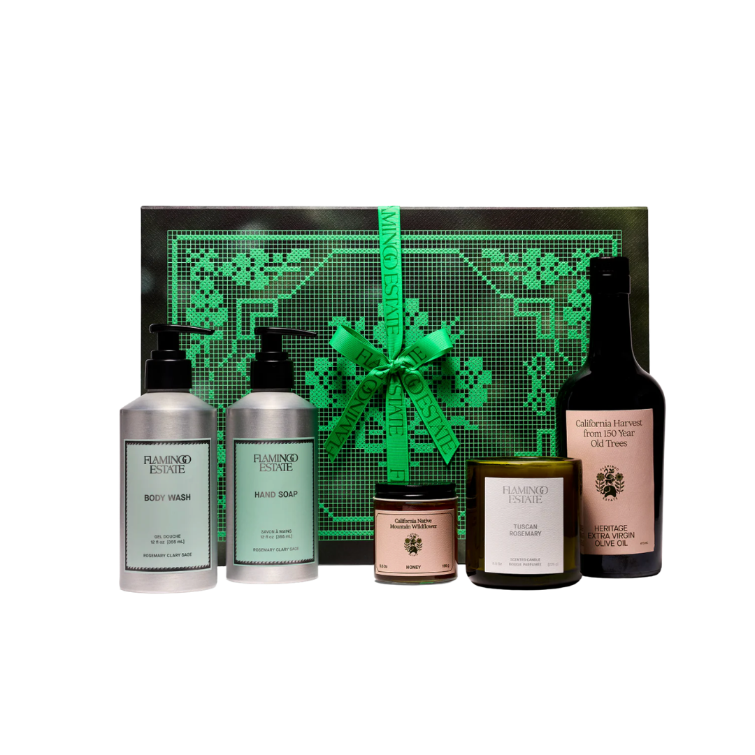 A Flamingo Estate gift set featuring a bright green botanical-patterned box, two pump bottles, and a jar of botanical honey.
