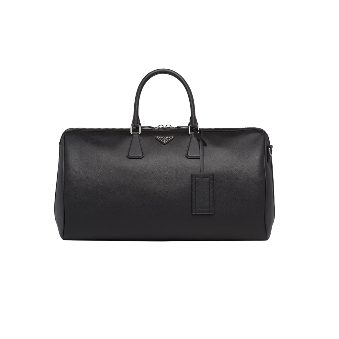 Black Prada Saffiano leather duffel bag with dual top handles, a hanging leather luggage tag, and a silver triangular Prada logo.