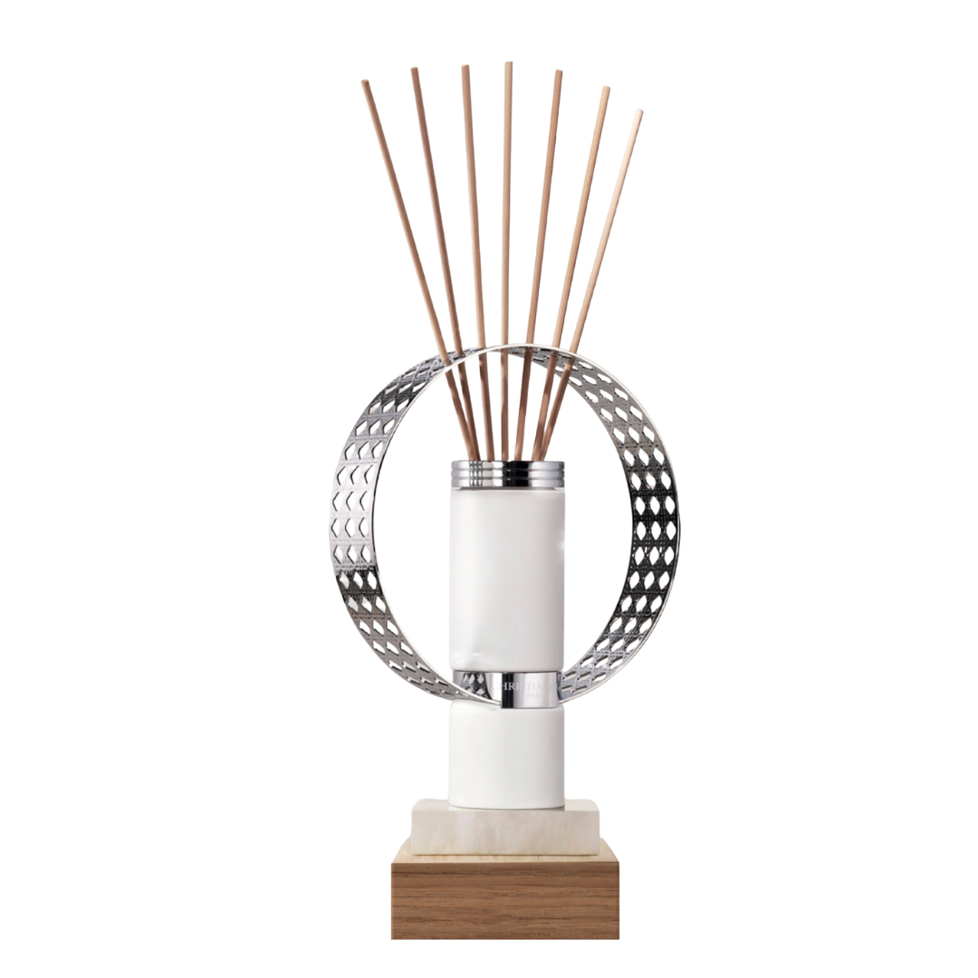 Modern Dior diffuser with a white marble and wood base, featuring a sculptural silver circular frame holding several natural wood sticks.