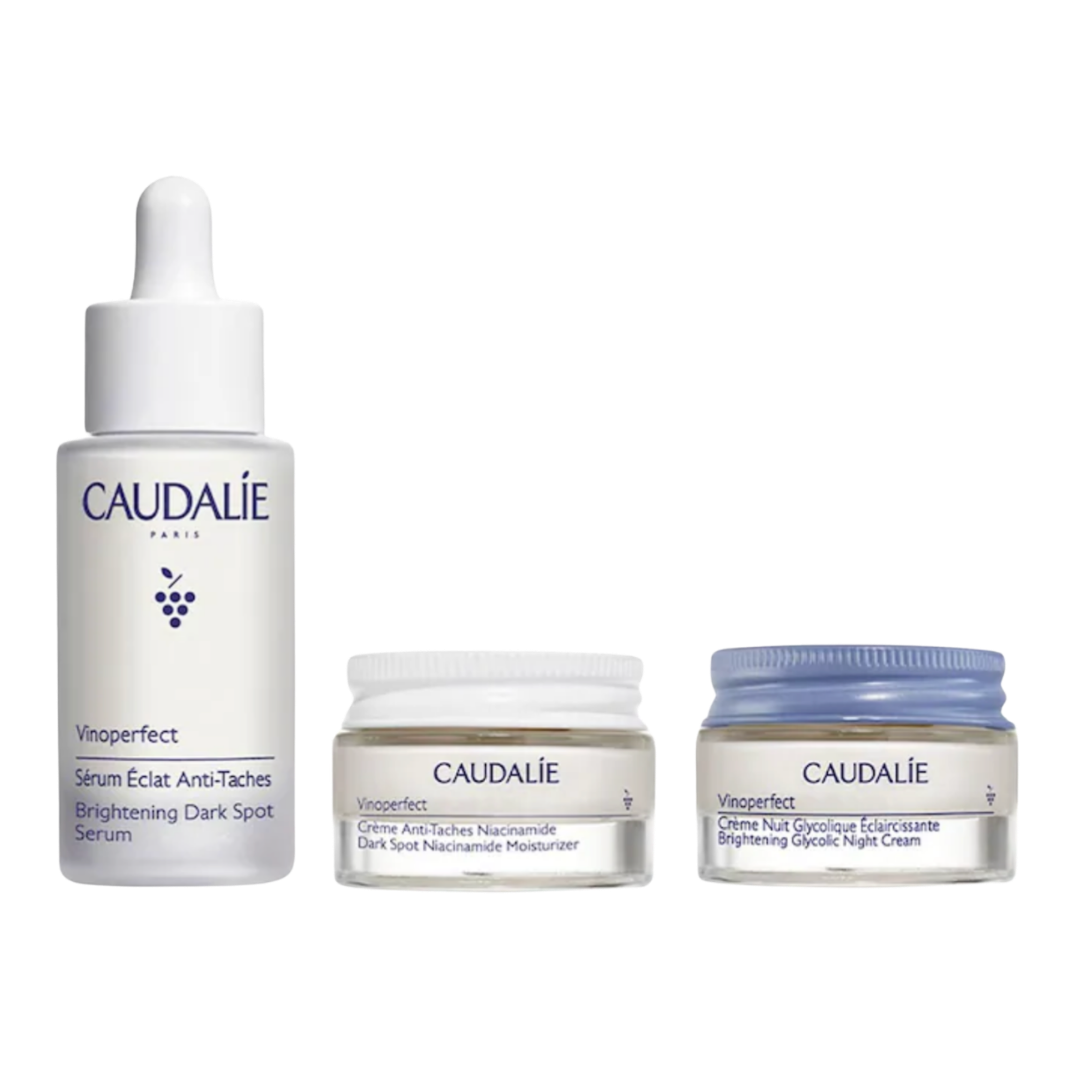 A Caudalie skincare set featuring a white serum dropper bottle and two small jars of brightening cream.