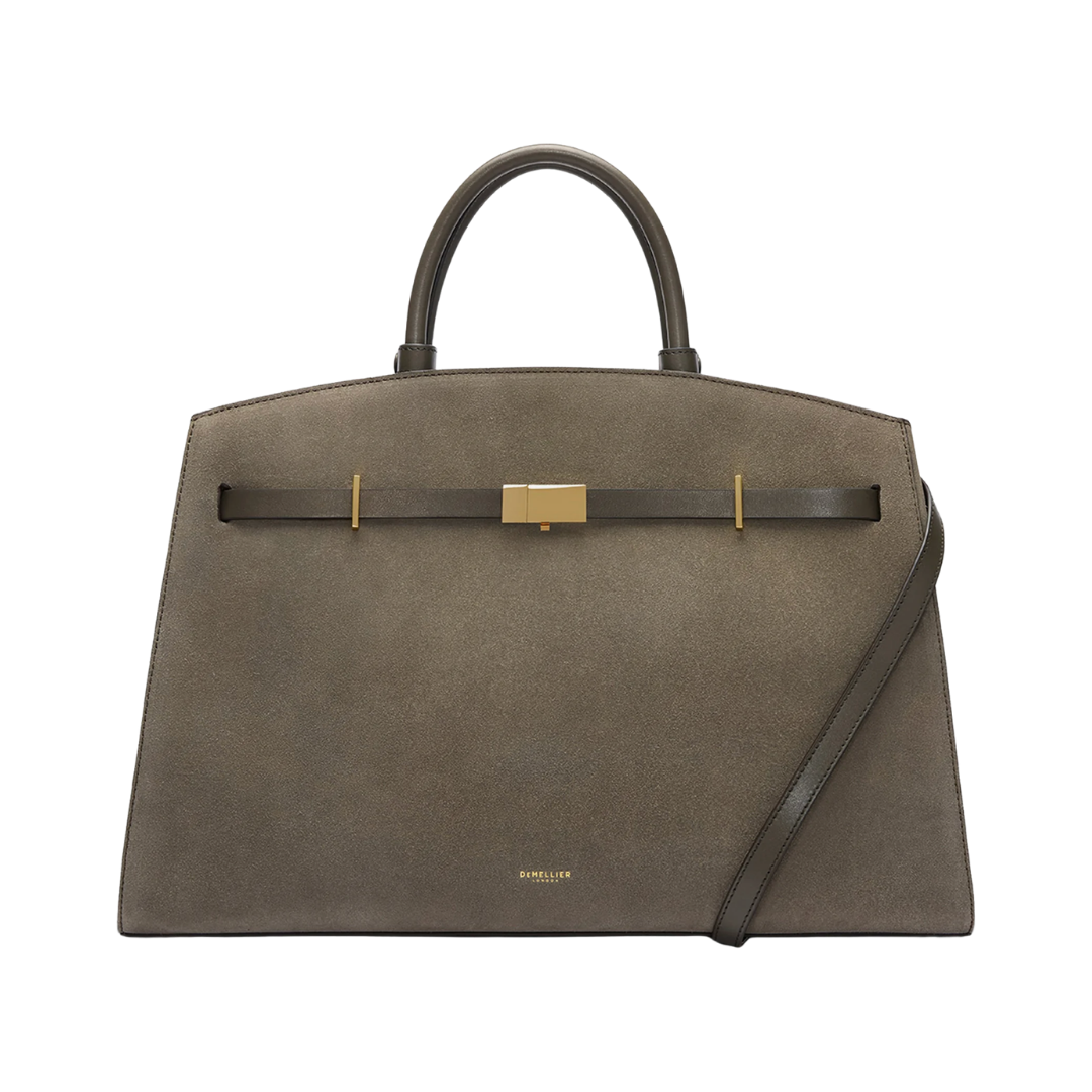 A structured taupe suede handbag with a top handle and a gold bar clasp across the front.