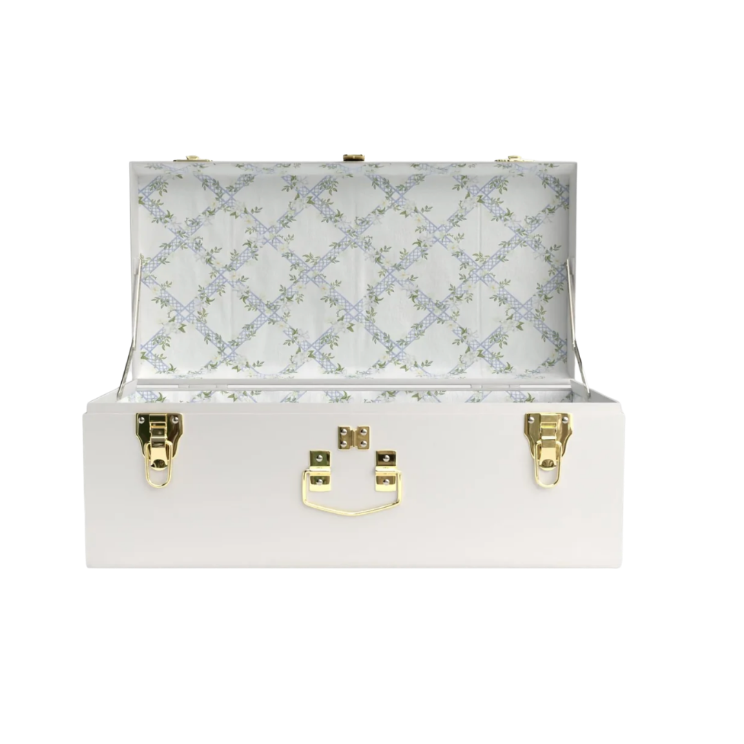 An open white luxury storage trunk with gold latches, featuring a delicate blue and white floral fabric lining inside.