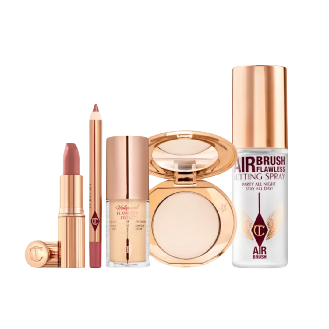 A Charlotte Tilbury makeup set including a lipstick, lip liner, setting spray, and a gold compact powder.