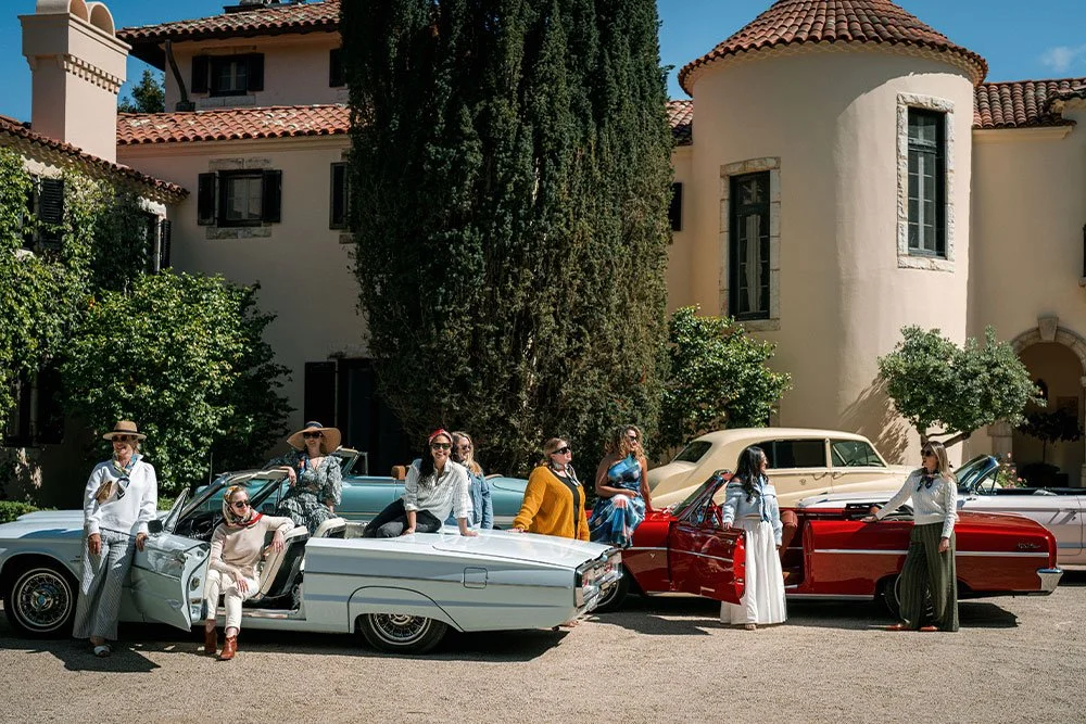 wedding guests posing with vintage cars in the estate
