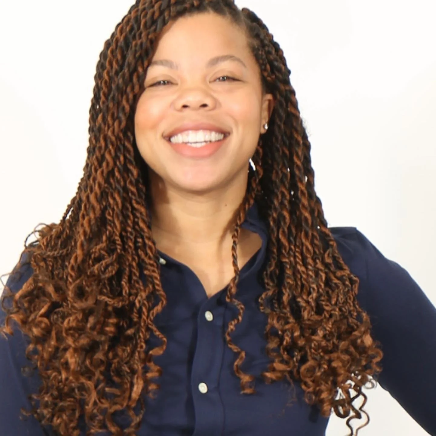 Professional portrait of an African American woman wearing pearl jewelry and a white outfit, smiling with a plain background.