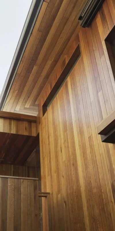 Interior view of a wooden ceiling and walls with a modern design, showcasing vertical and horizontal wood paneling in a warm, natural finish.