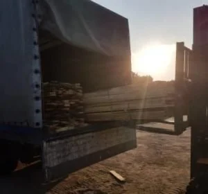 Forklift unloading lumber from a truck at sunset