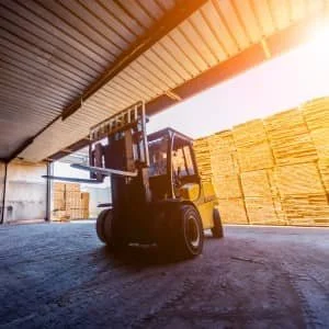 Forklift in a lumber warehouse, sunlight, wooden planks stacked