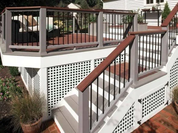 Outdoor staircase and deck with wooden railings, lattice panels, and potted plants.