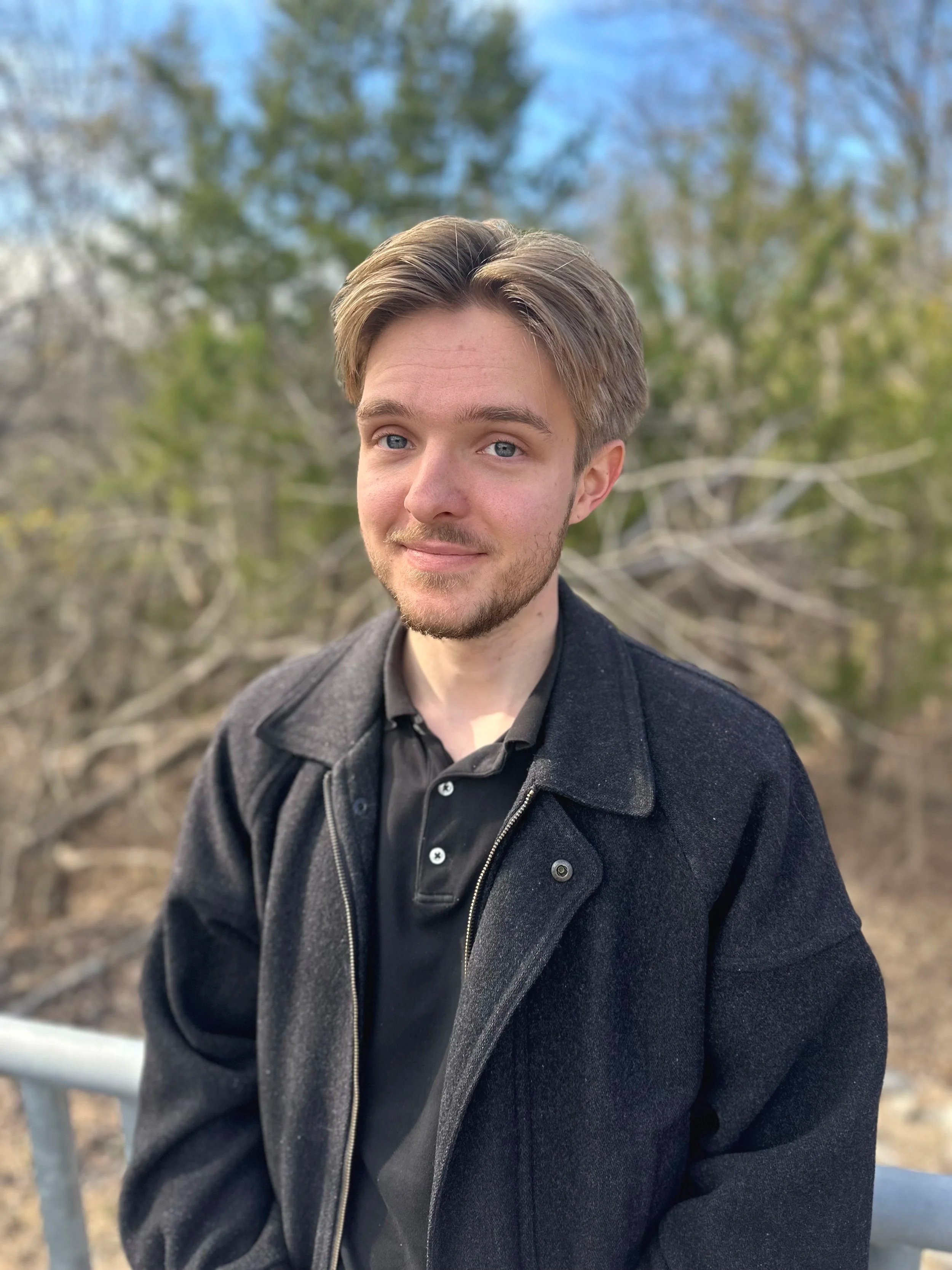Man in black top standing on a bridge, smiling