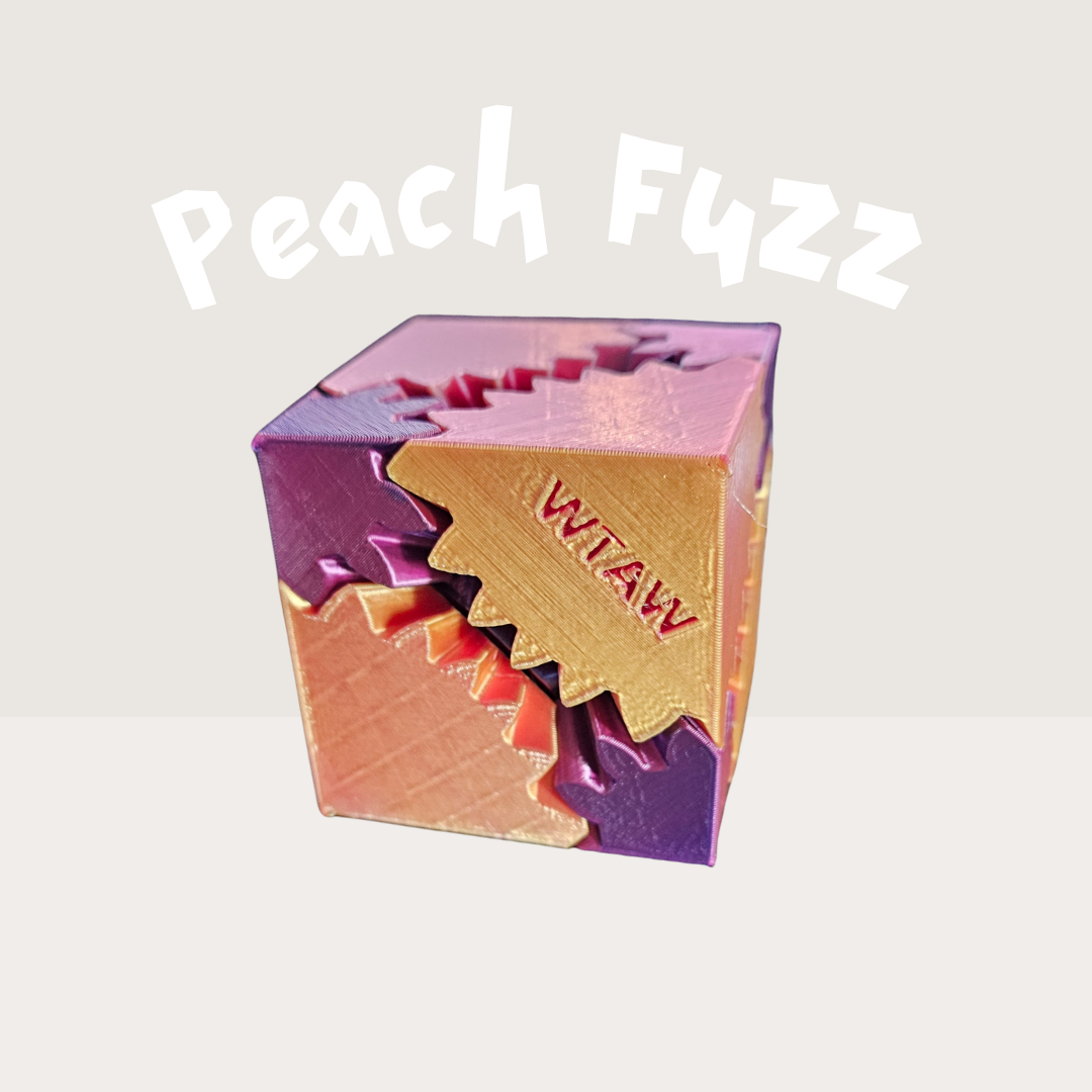 Peach Fuzz pastel 3D-printed fidget cube with peach, gold, and lavender gears and 'WTAW' text.