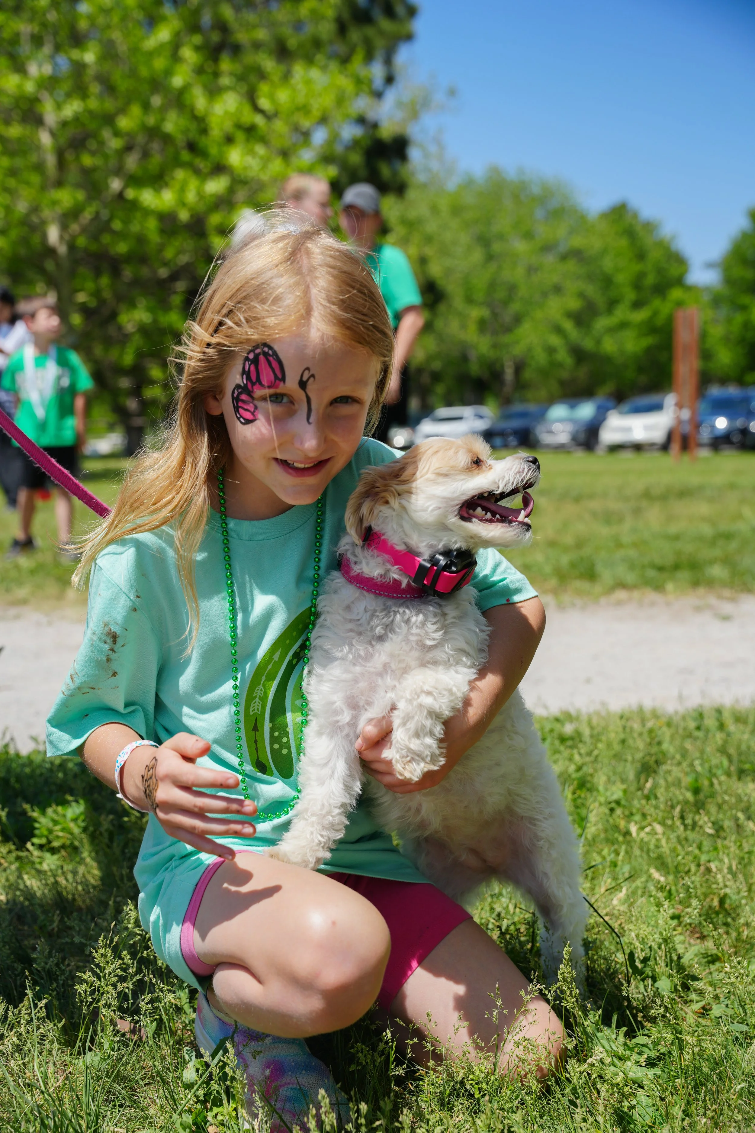 young girl with face paint hugs a dog