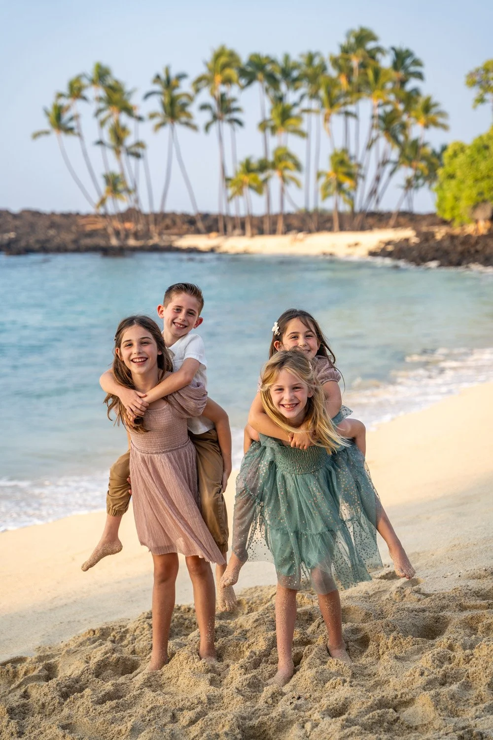 Children on a beach giving each other piggy back rides in Hawaii