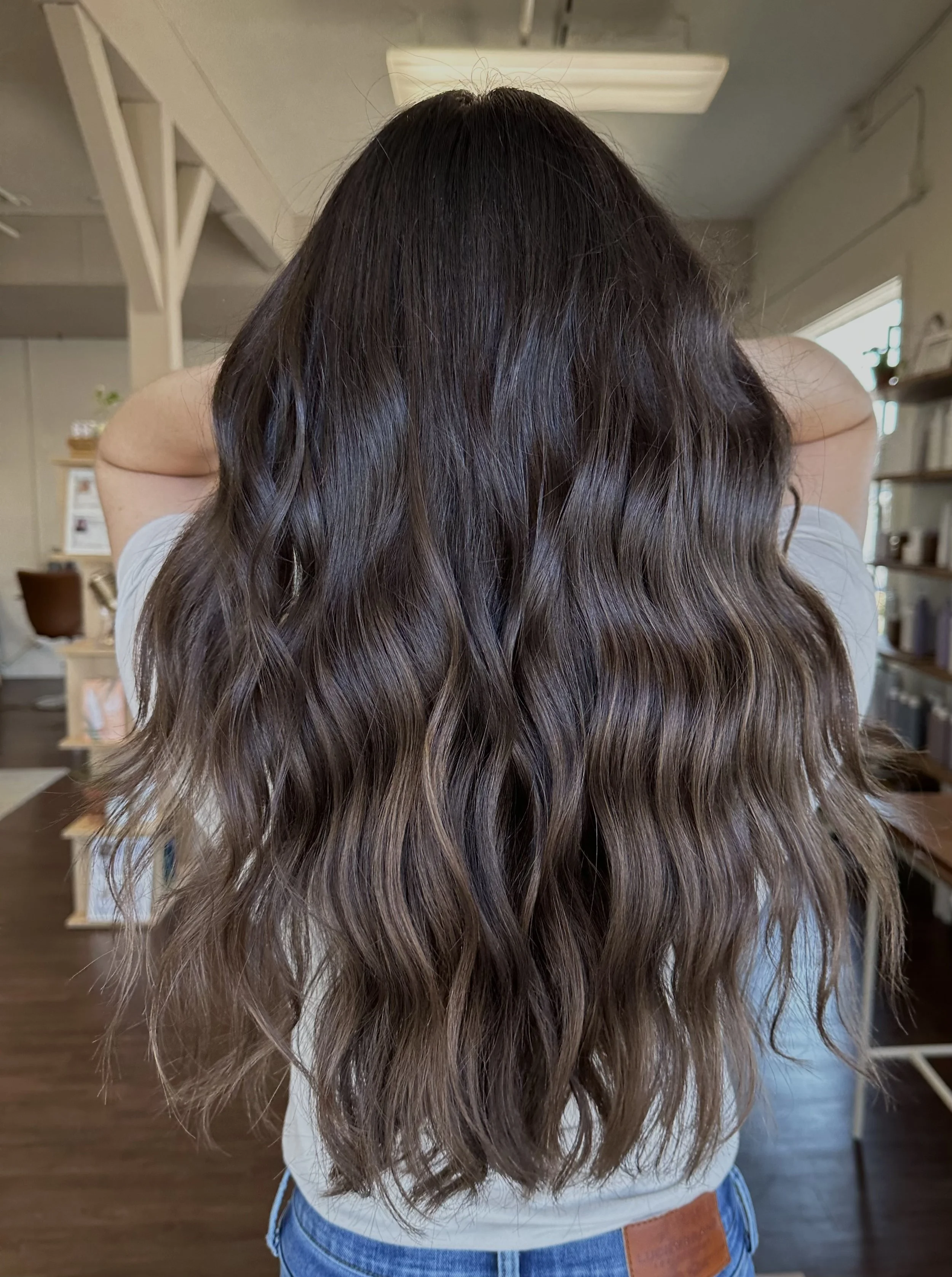 Person with long wavy brown hair in a hair salon.