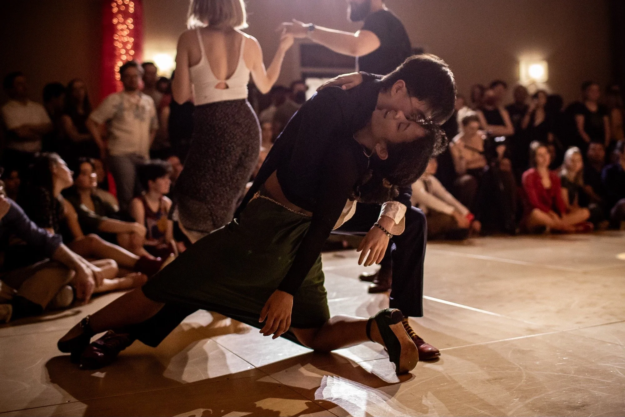 People dancing passionately on stage with audience watching.