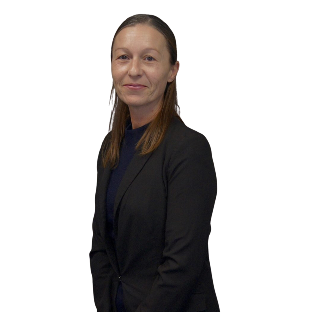 A woman with light skin, straight brown hair, and a slight smile, dressed in a black blazer over a dark top, standing against a plain white background.