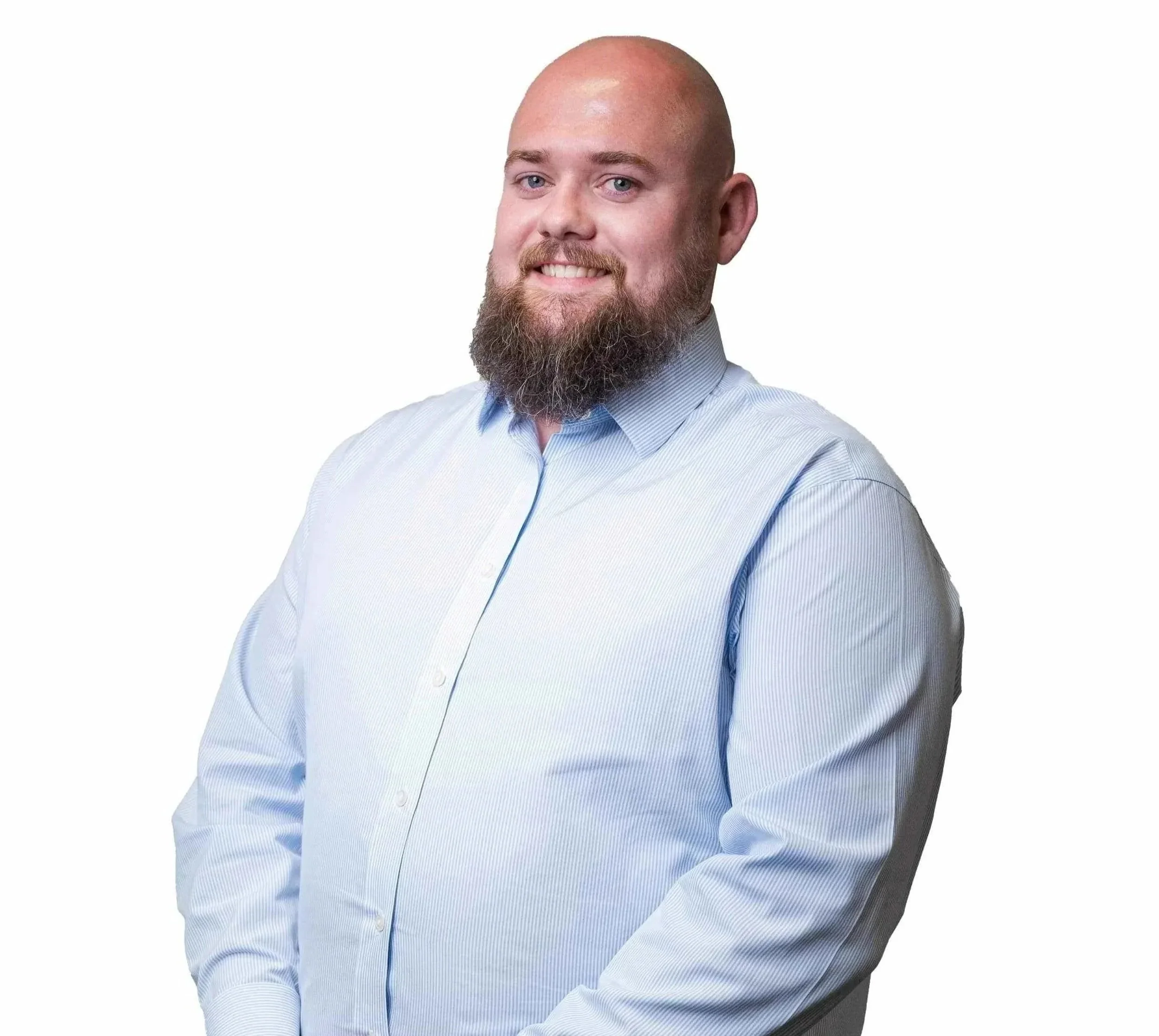 A man with a beard and bald head wearing a light blue dress shirt, smiling and posing with arms crossed against a white background.