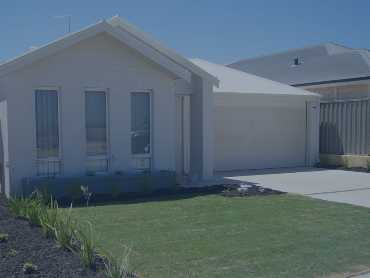 Front view of a modern white house with three tall narrow windows, a garage, and a small lawn with young plants.
