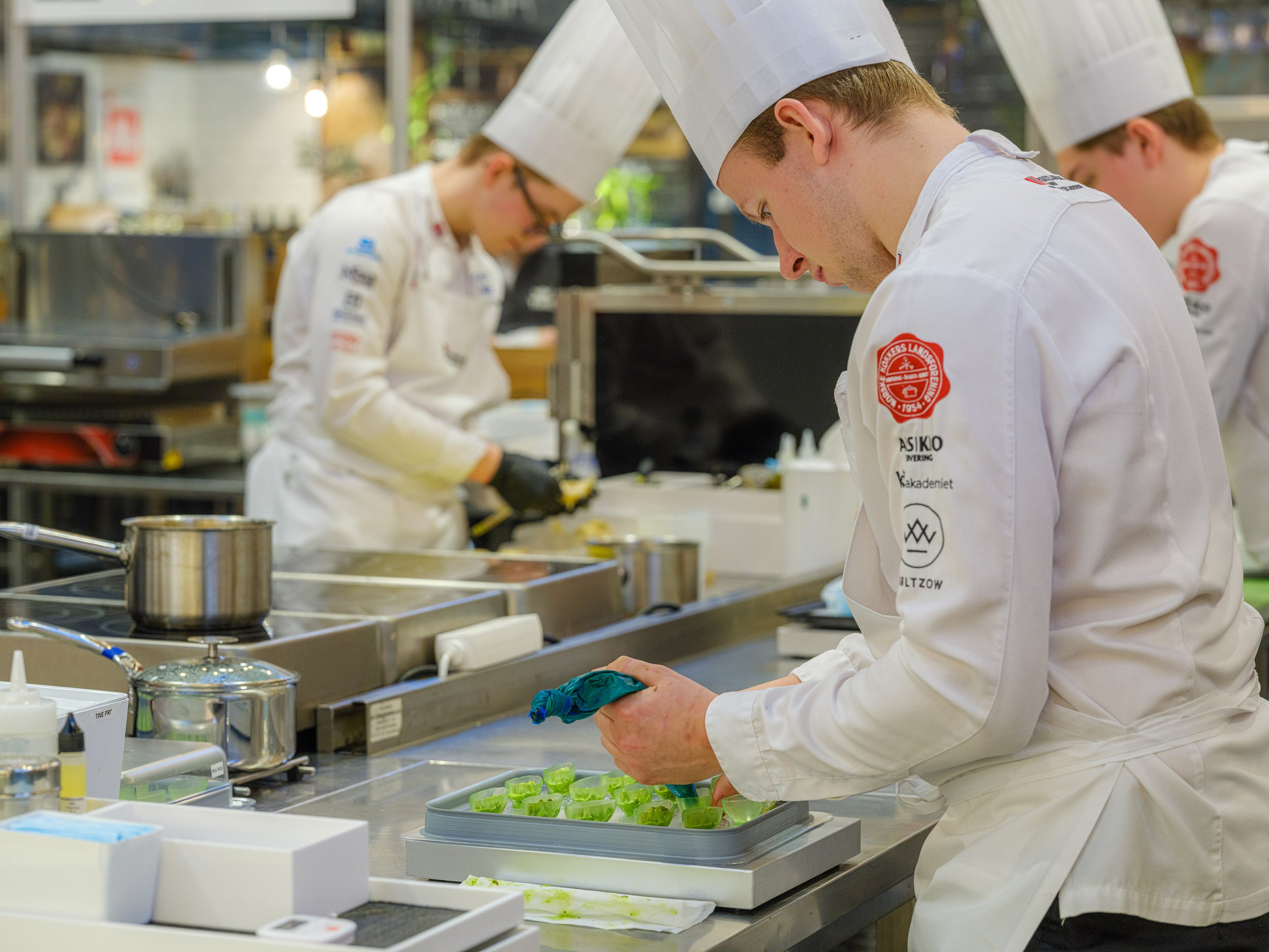 Kokkestudent som forbereder ingredienser i et profesjonelt kjøkken.